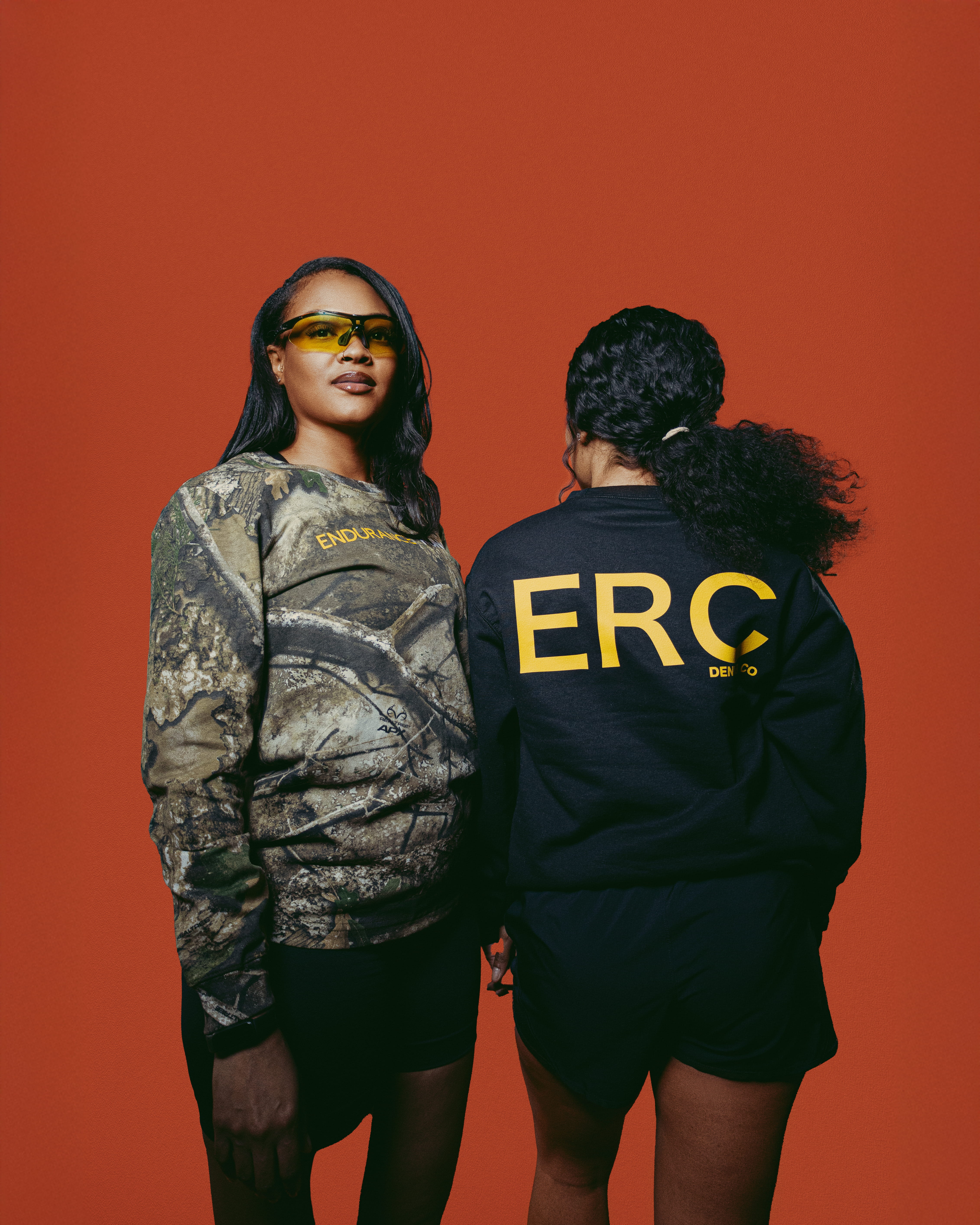 two endurance run club members standing together in studio wearing branded running apparel