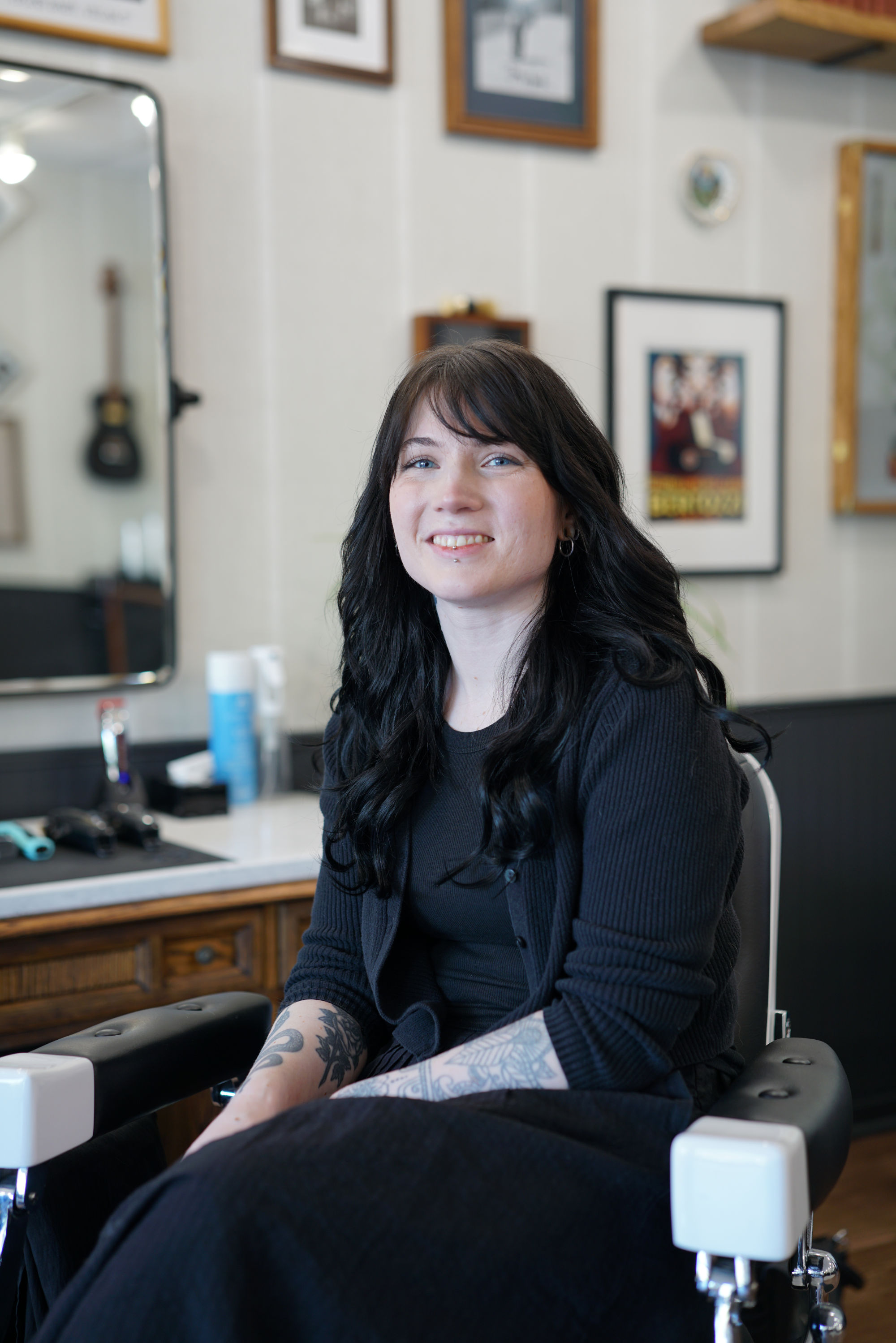 Portrait of Krista Chaplin, barber at Calderone’s Barbershop, seated inside the shop