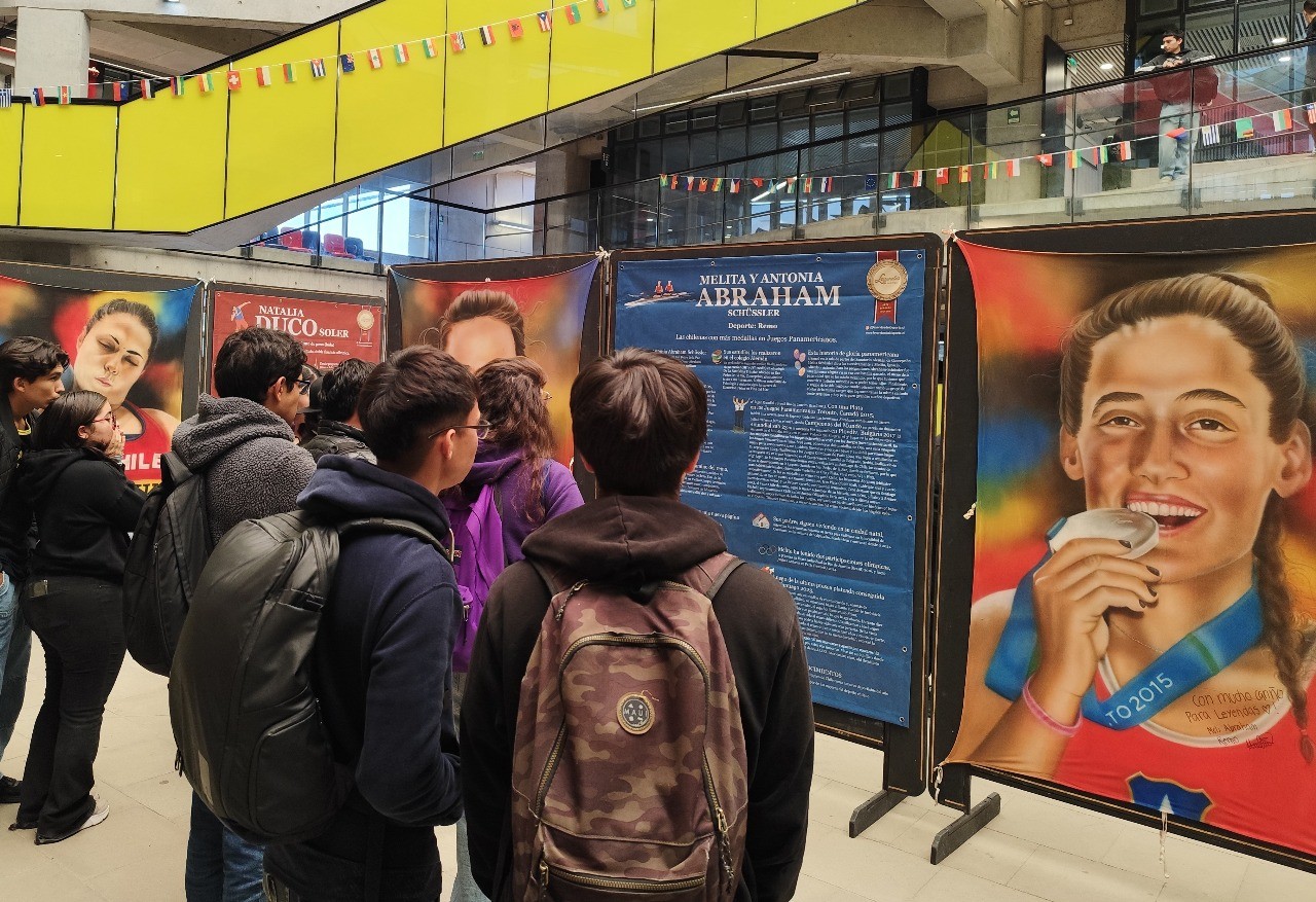 Espectadores observando la pintura de las Hermanas Abraham, remeras chilenas, en la exposición Leyendas del Deporte en USACH.