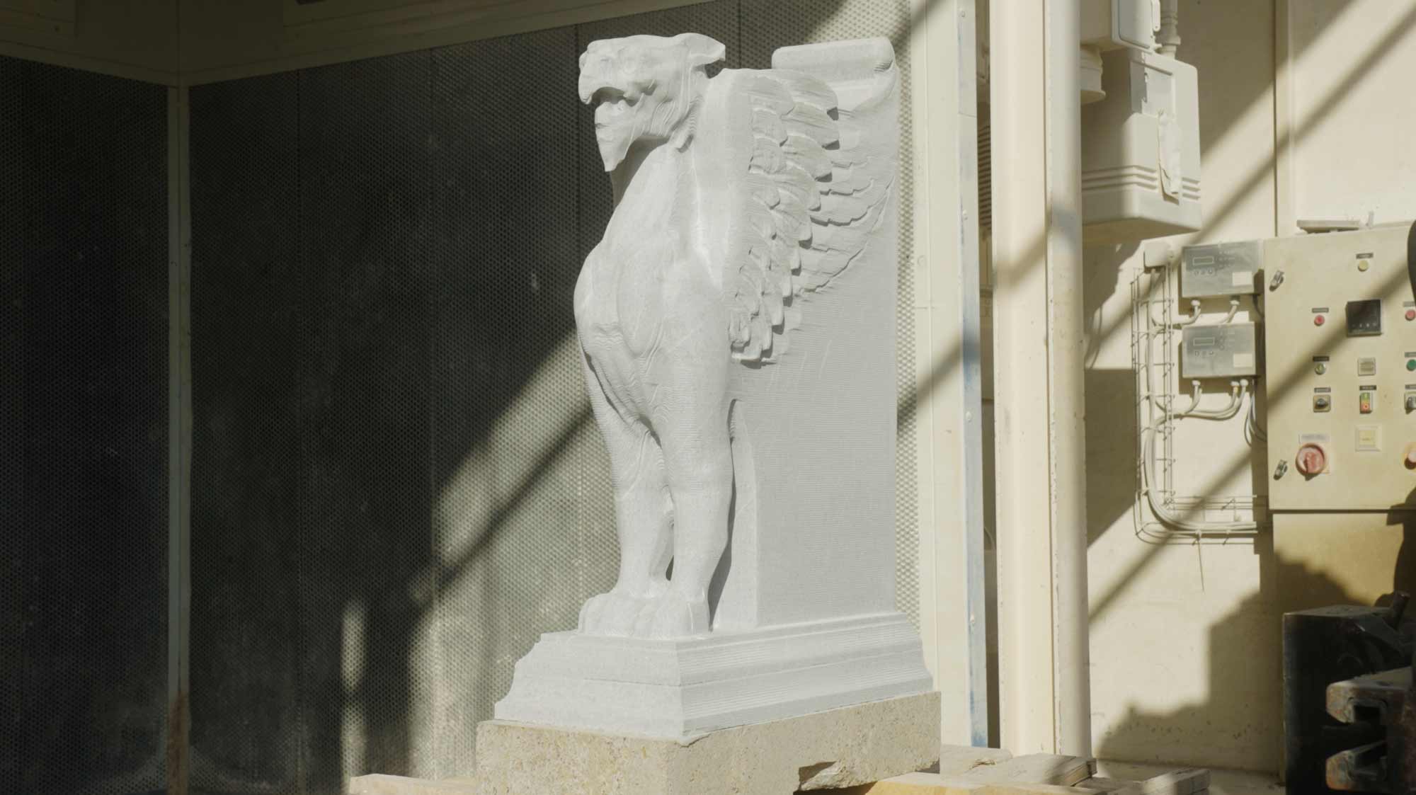 White griffin statue in a workshop, surrounded by machinery, highlights strategic film production and storytelling in campaigns.