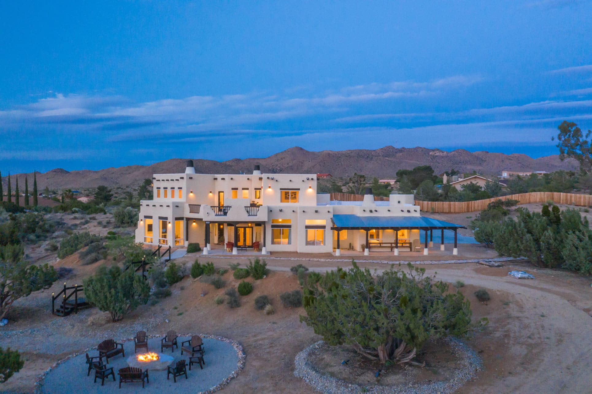 Desert retreat location, featuring a white villa in the desert with a communal firepit outside.