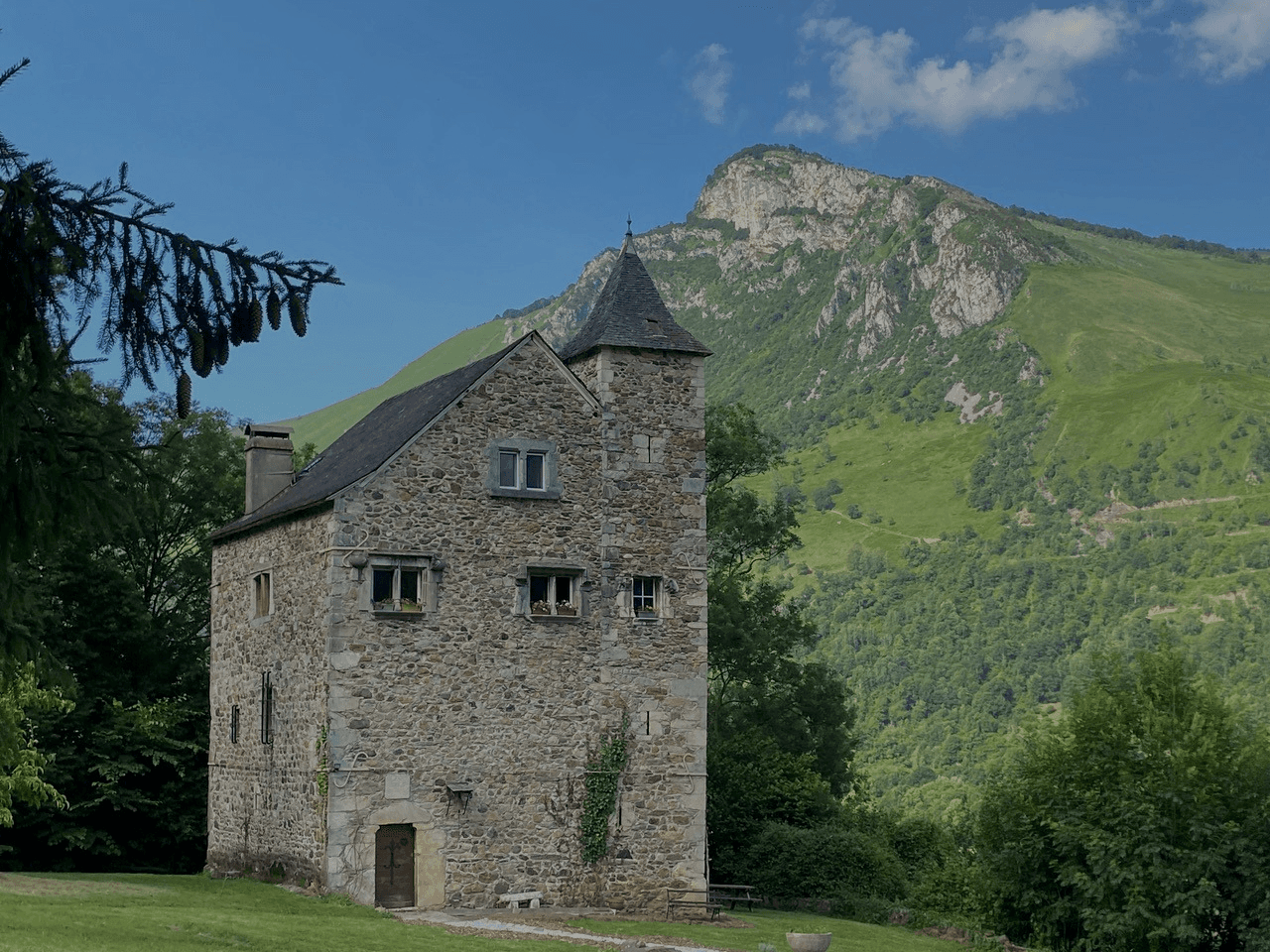 Exterior view of the historic Château de Gère, a 14th-century hunting lodge once used by King Henry IV, set against the majestic backdrop of the Ossau Valley in the Pyrenees.
