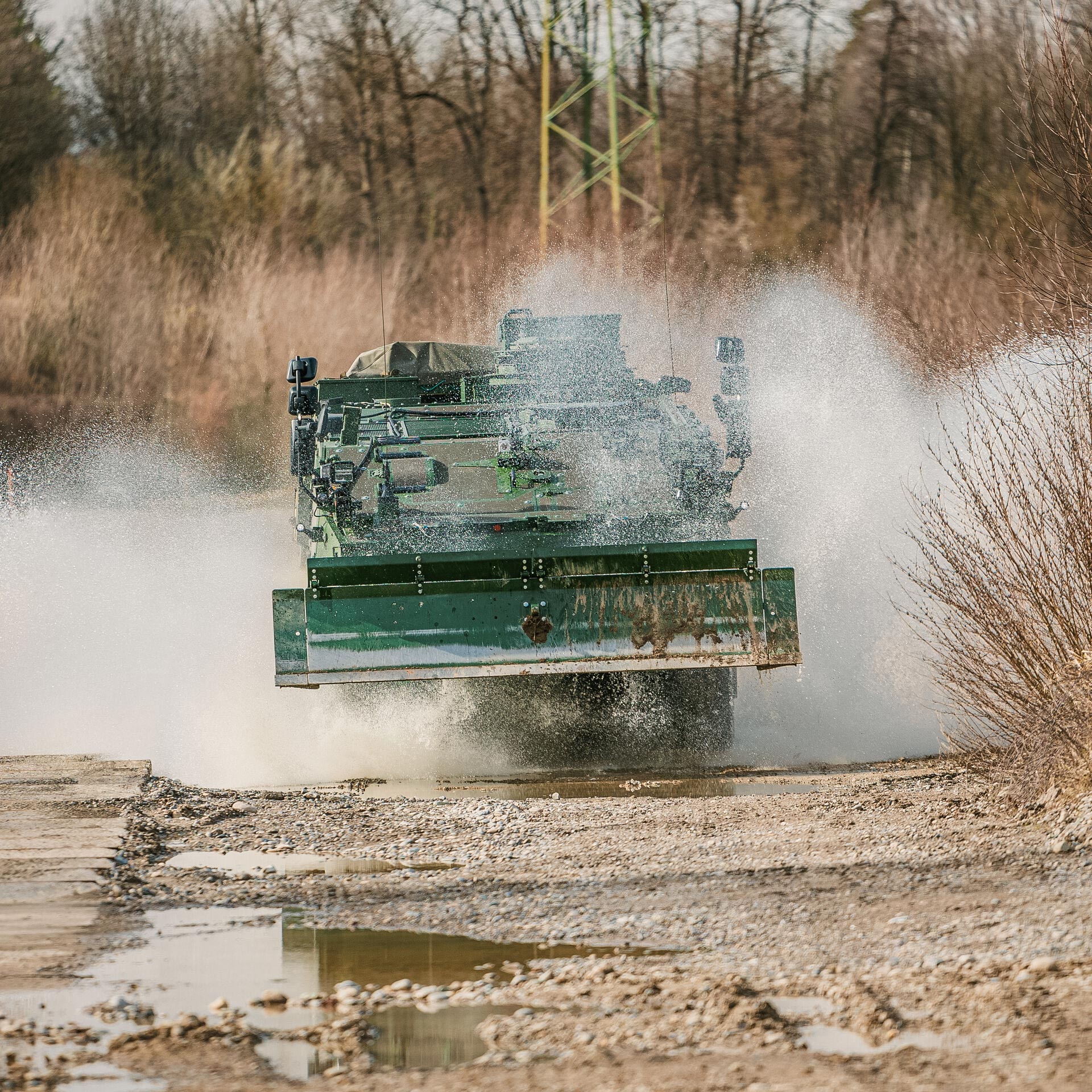 GCS Dozer Blade on a Piranha IV armoured vehicle during high-speed combat engineering operations in wet terrain.