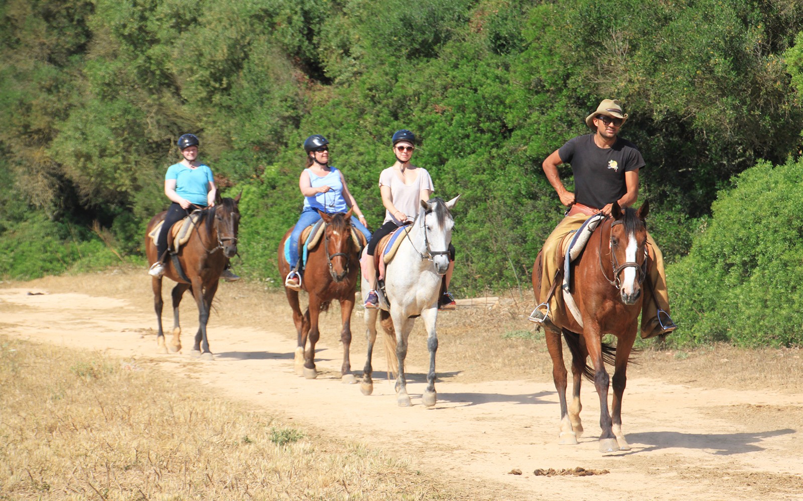 Jinetes a caballo en un sendero arenoso cerca de la playa en Mallorca.