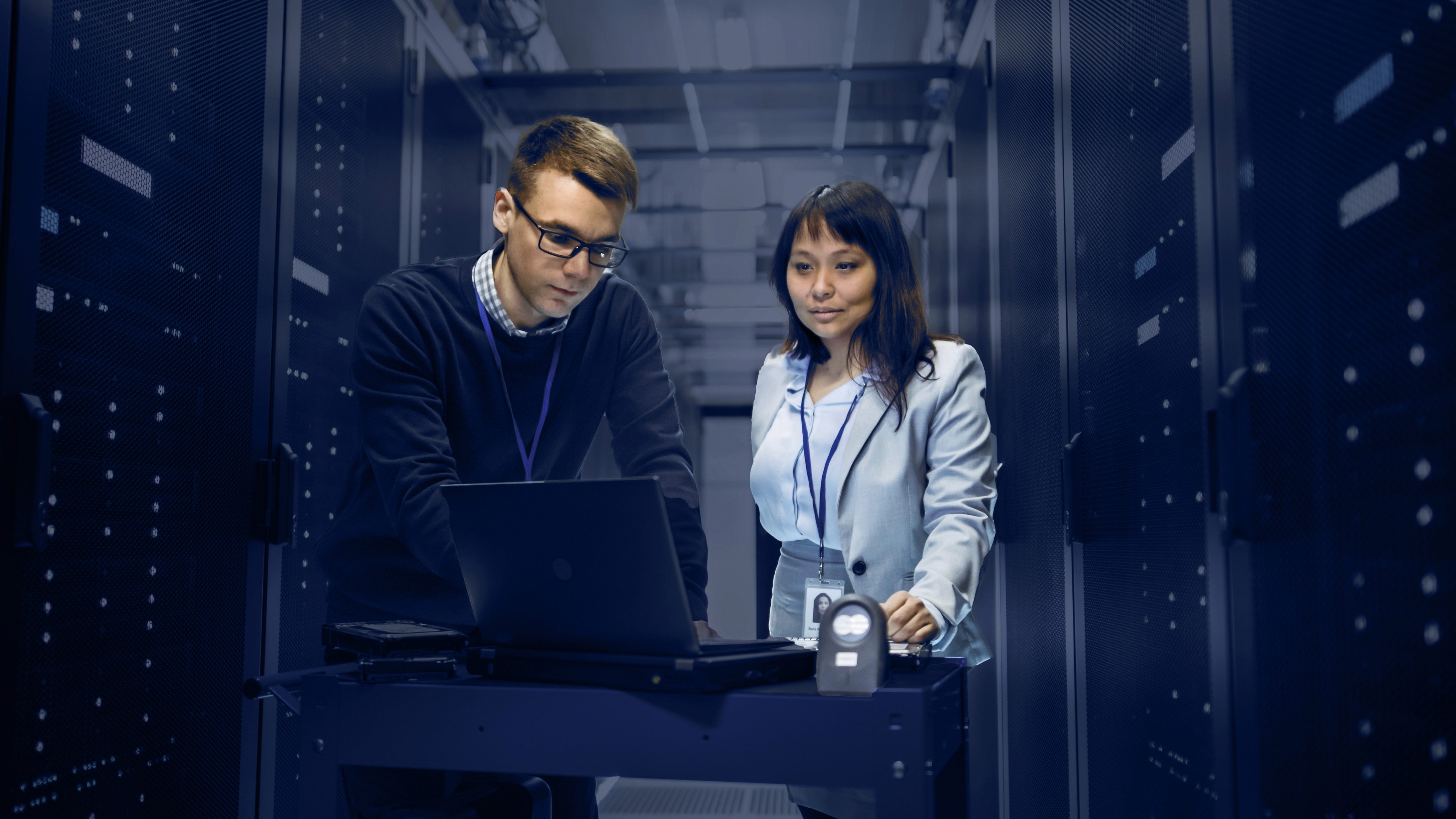homem e mulher operando um notebook em um datacenter