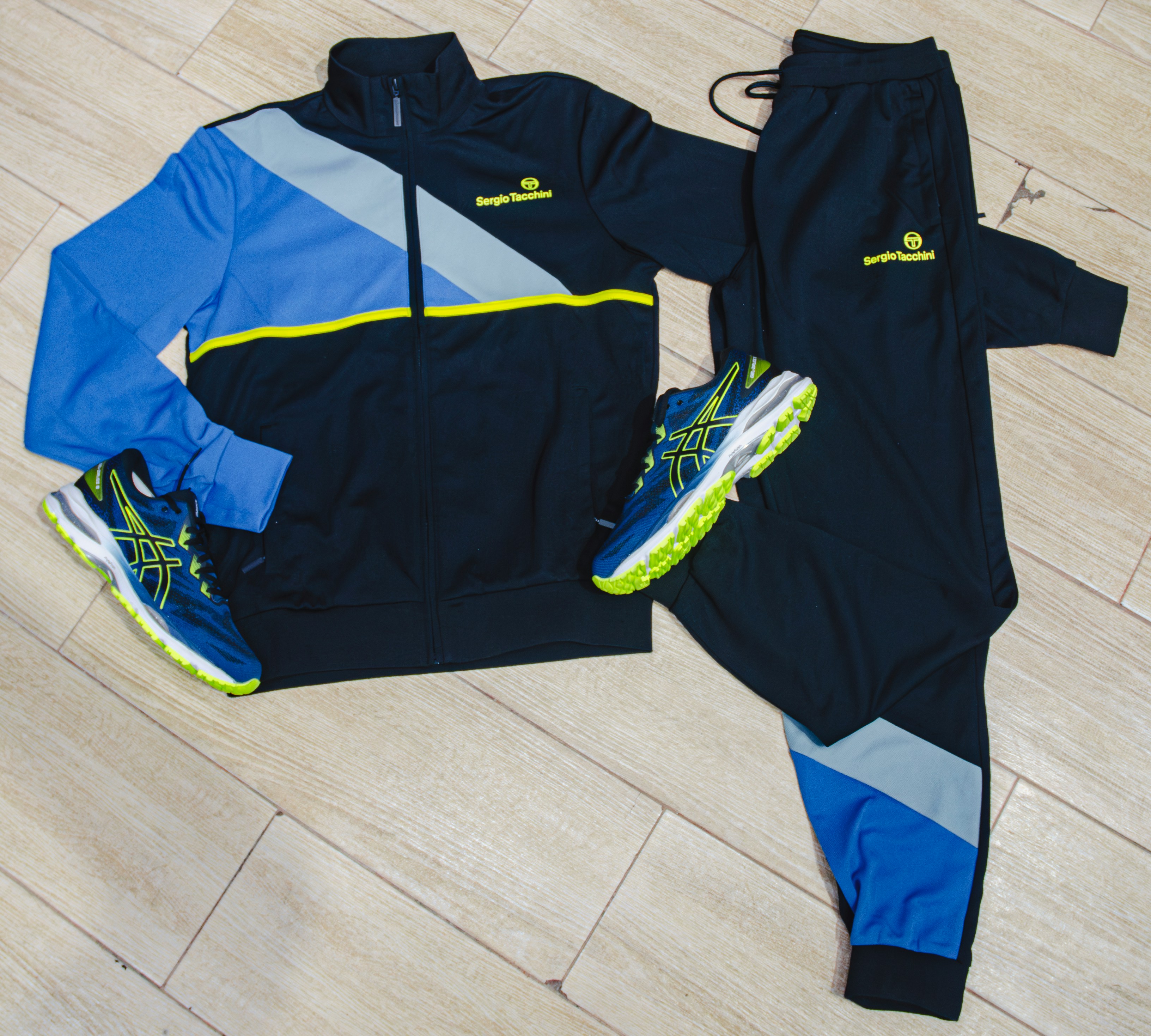 a pair of tracksuits and a pair of running shoes on a wooden floor