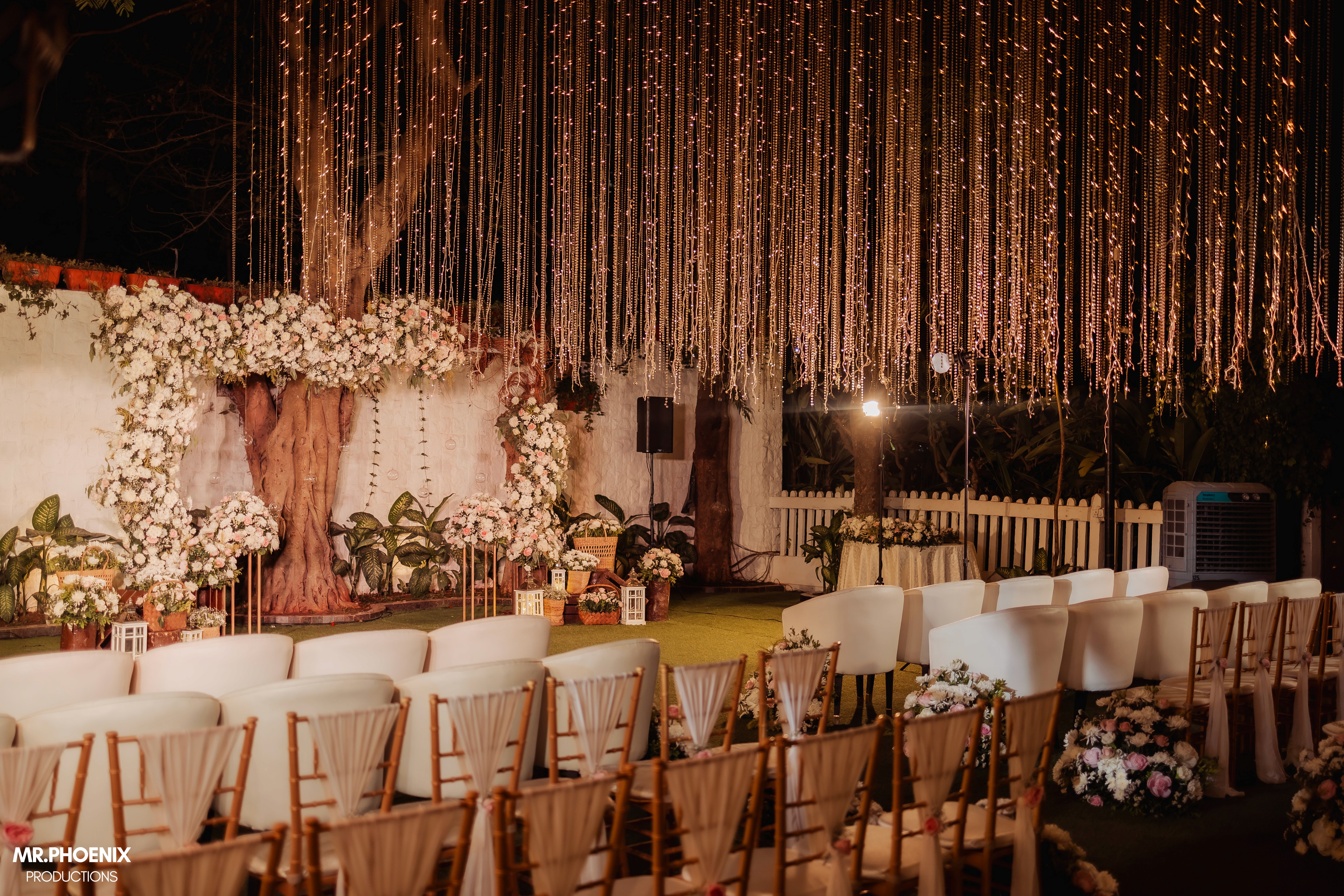 Vineyard rows under leafy foreground frame a Tuscan villa on a misty hill