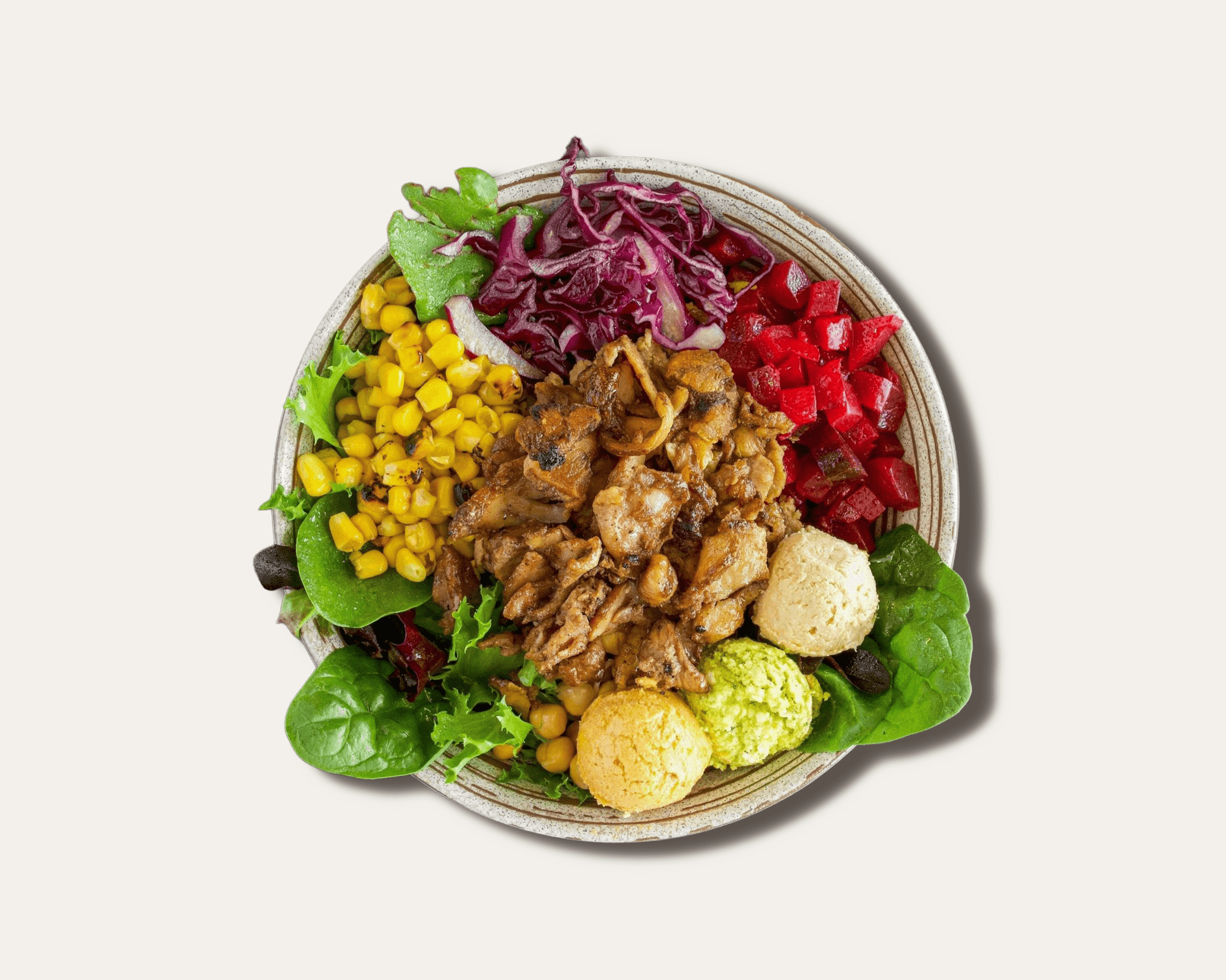 Top-down view of a customizable Mediterranean grain bowl with greens, protein, and assorted toppings.