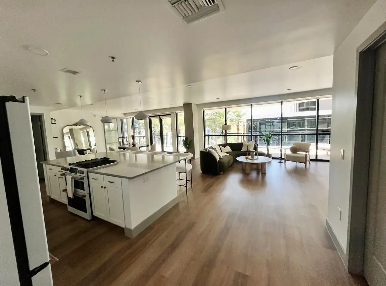 Professionally cleaned modern living area and kitchen featuring vacuumed hardwood floors, dusted furniture, and a spotless island stovetop.