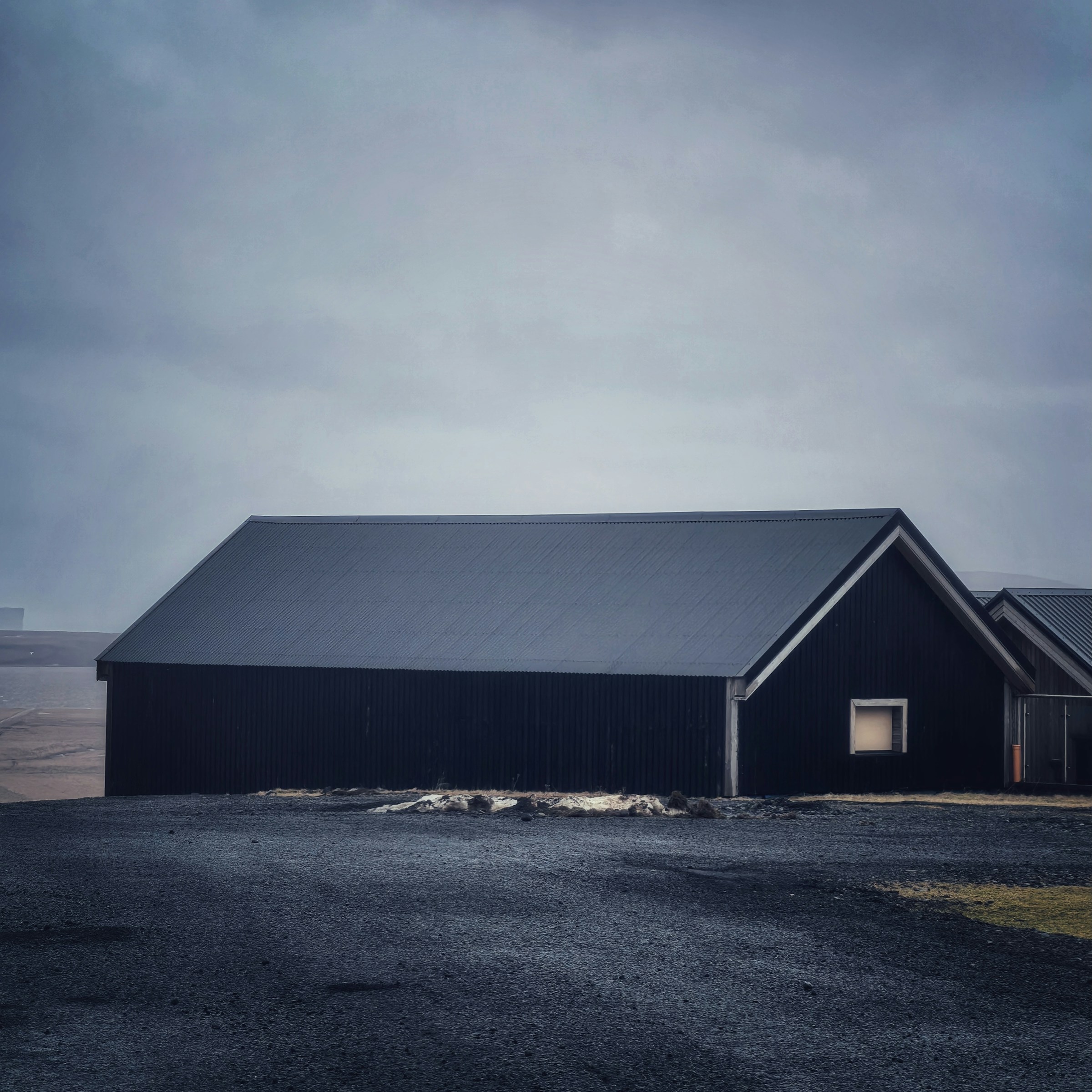 Dark pitched house under a heavy sky