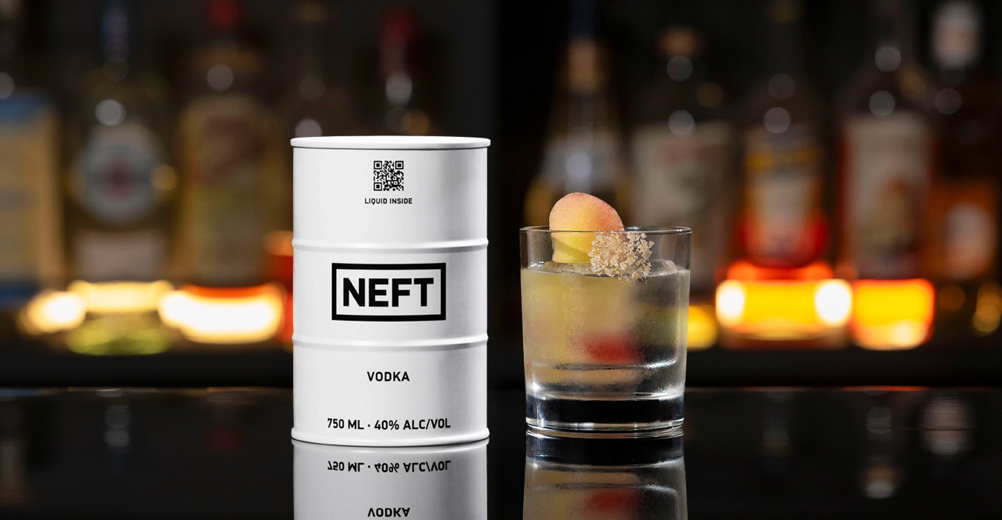 A NEFT Barrel and a glass of Peach Vodka Old Fashioned on a bar counter.