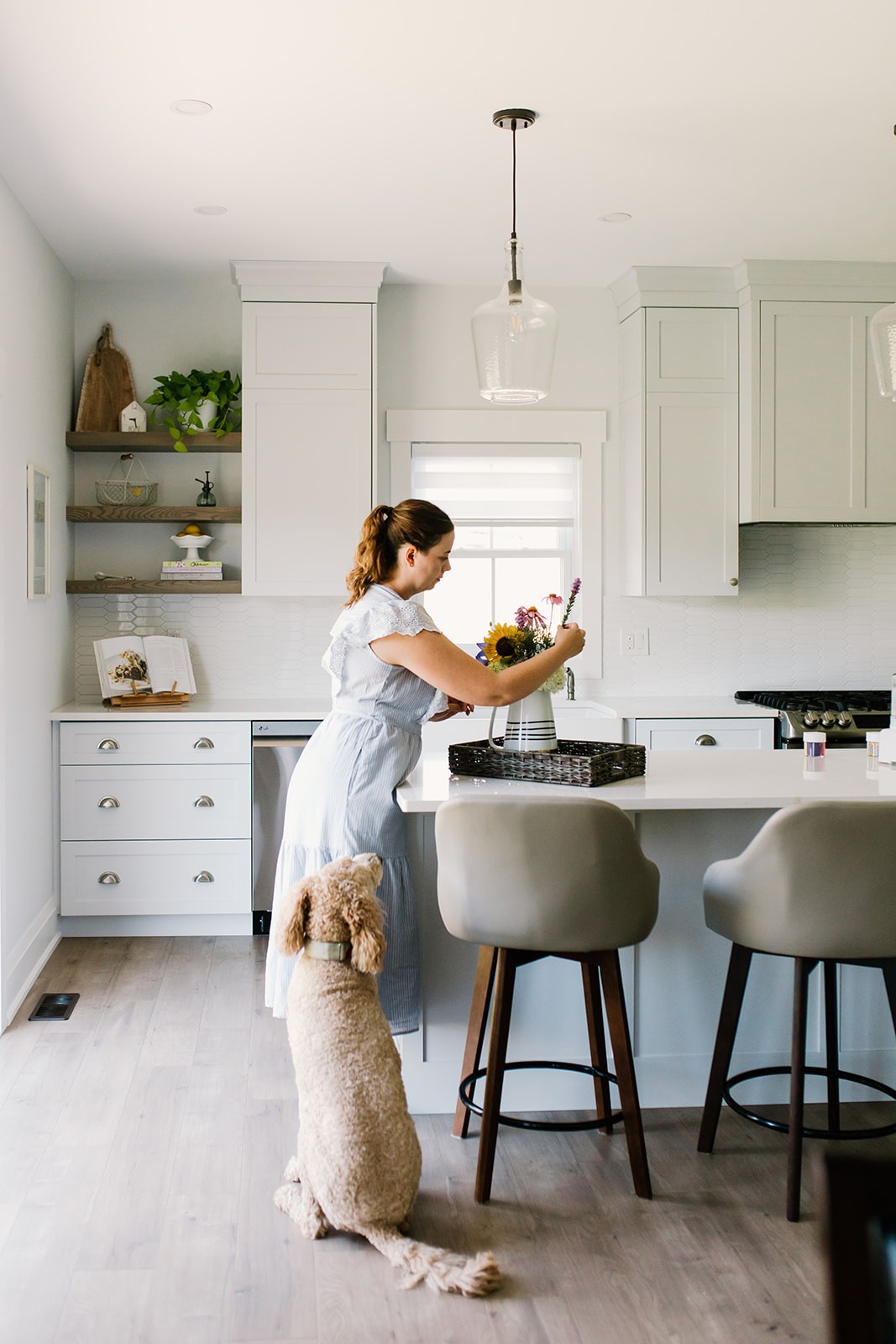 View of the French countryside through a stone villa’s open living room, with sofas and trees framing the scene