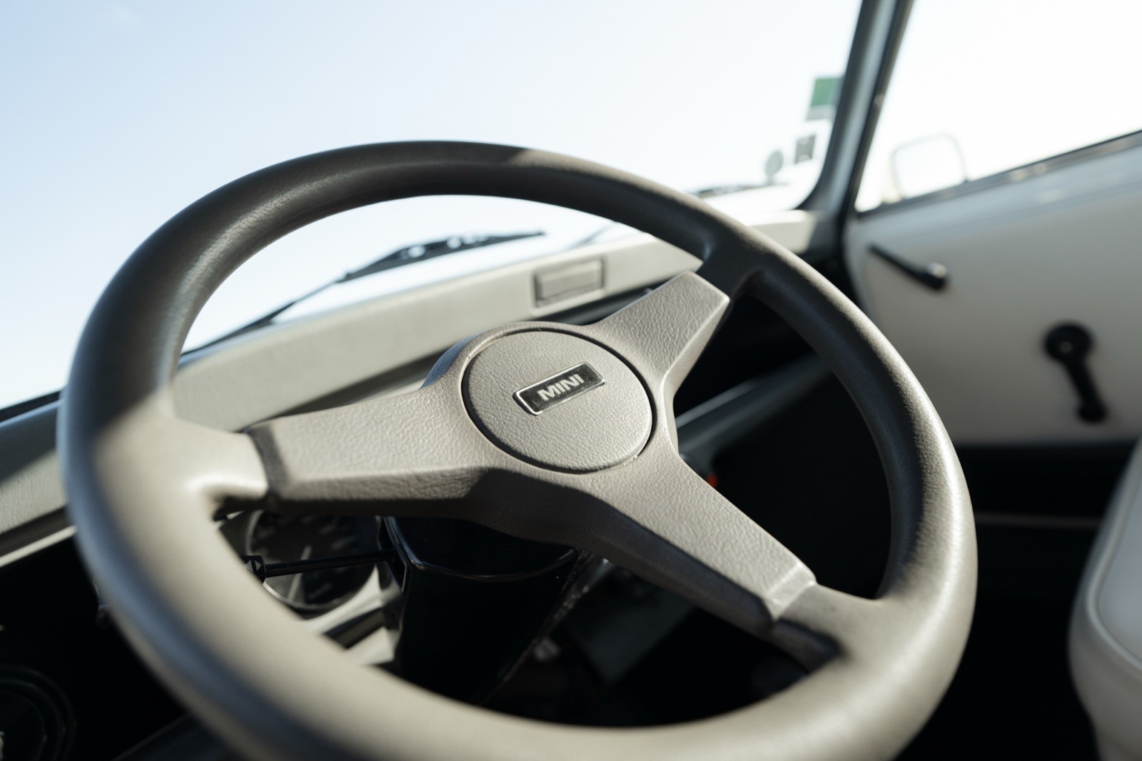 Close-up of a vehicle's steering wheel with a blurred dashboard in the background, showcasing an angle view.
