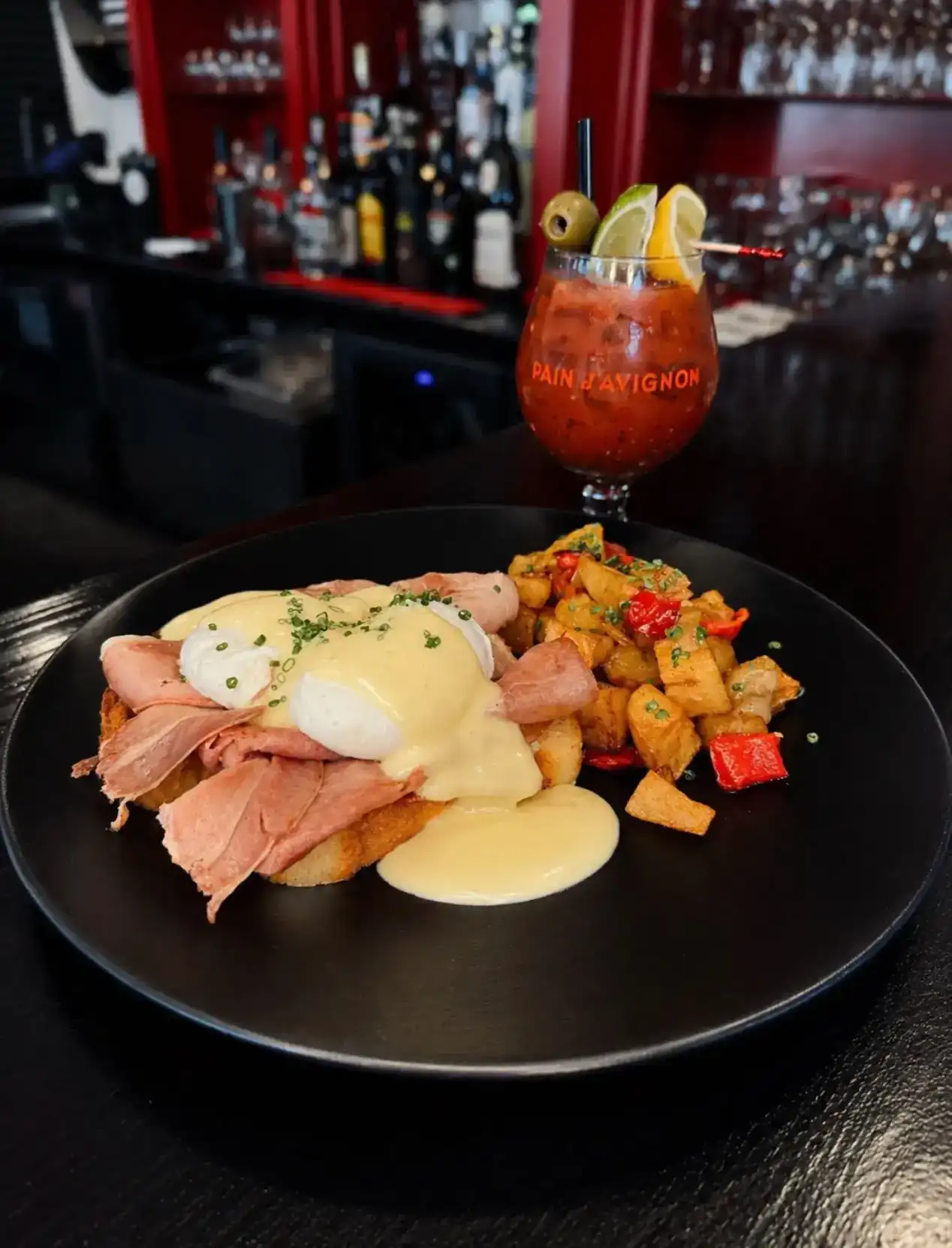 Brunch plate with eggs Benedict, roasted potatoes, and cocktail at Pain D’Avignon.
