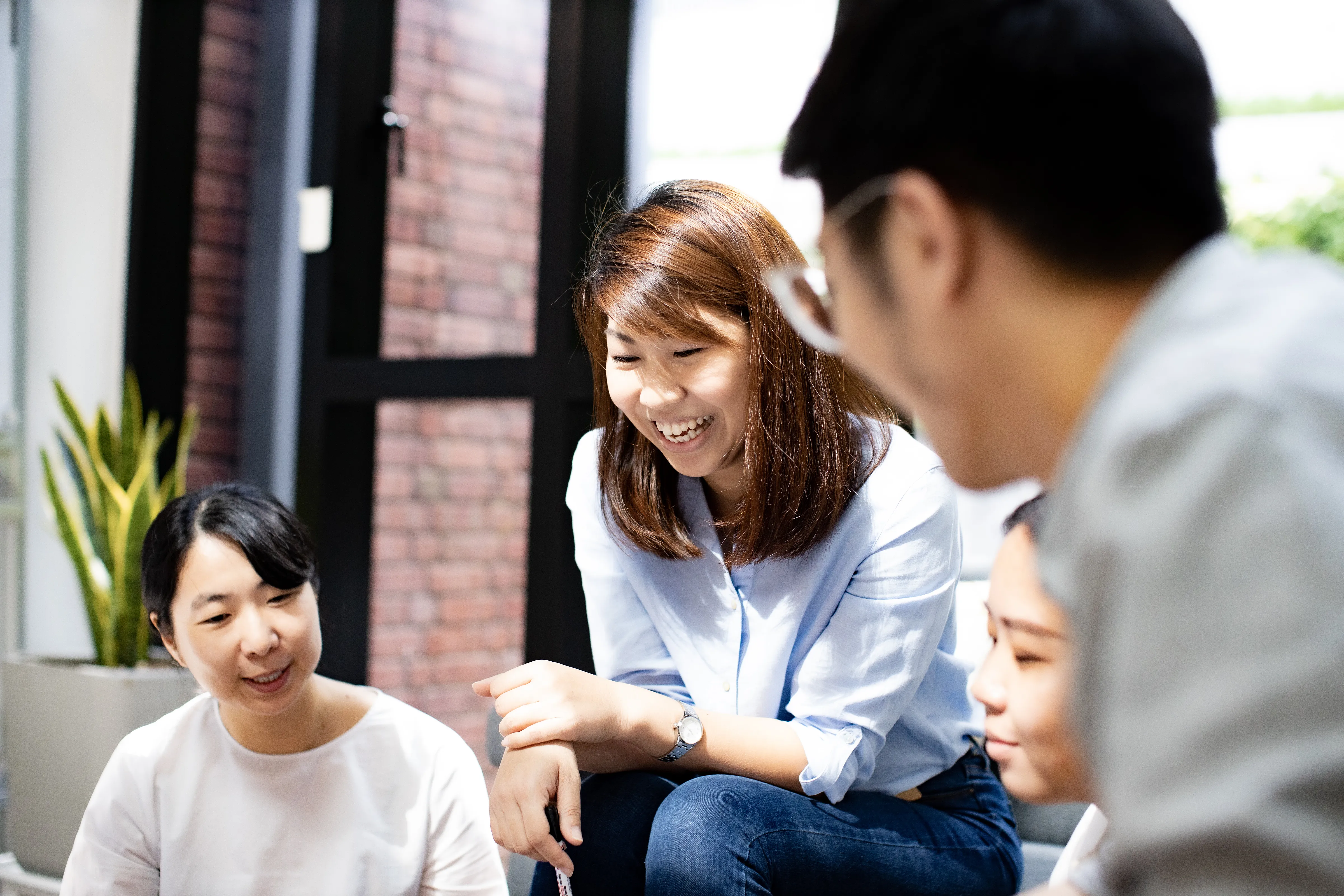 An image of a group of people share a laugh in a bright, modern space.