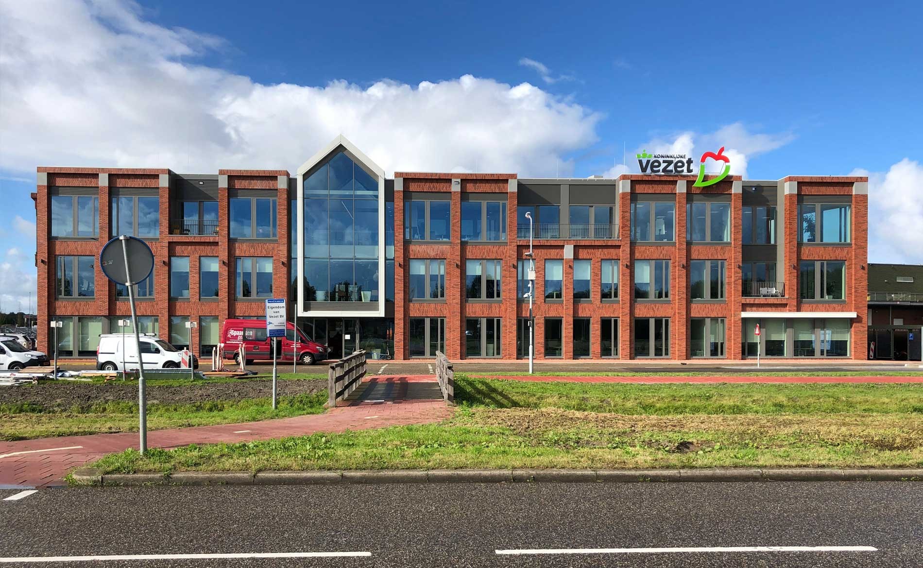 Een rood bakstenen gebouw met de naam "vezet" erop tegen een blauwe lucht.