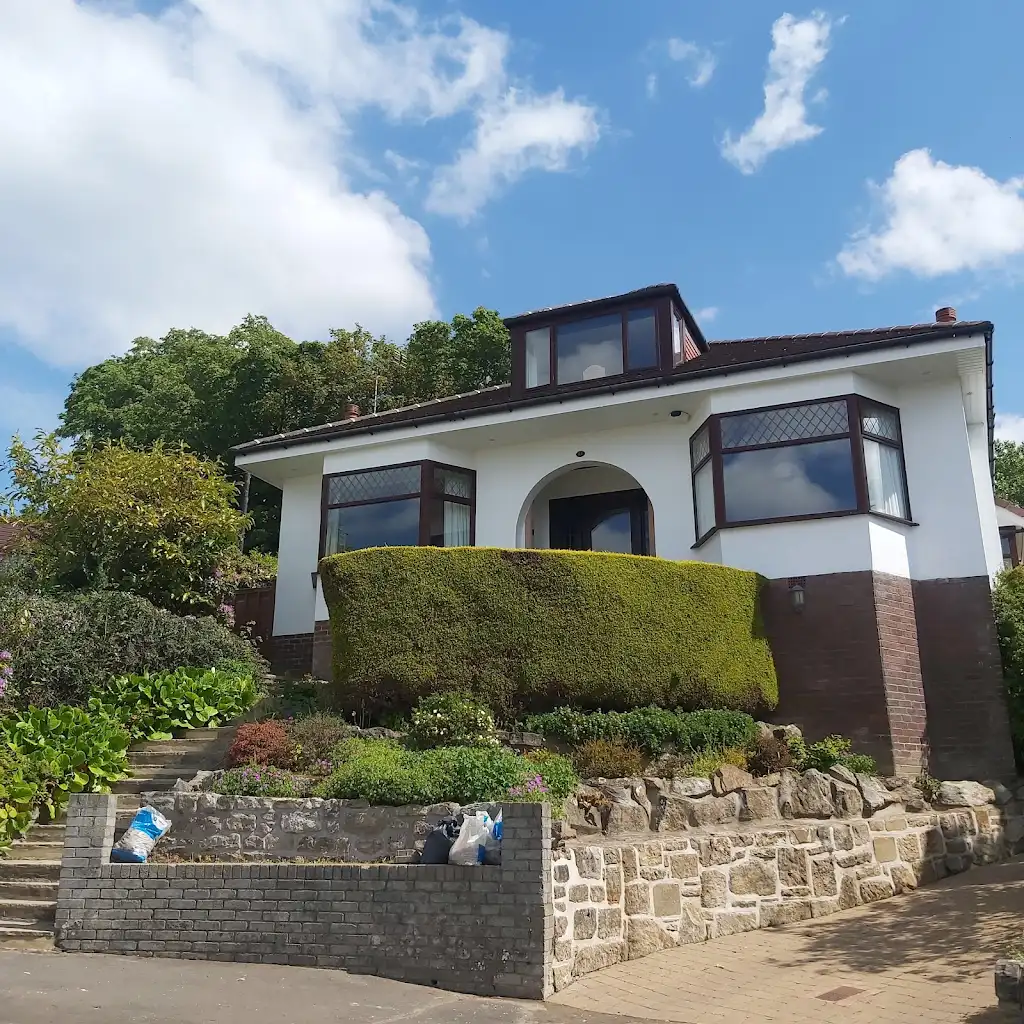 A small house with a drive and steep steps leading to front door