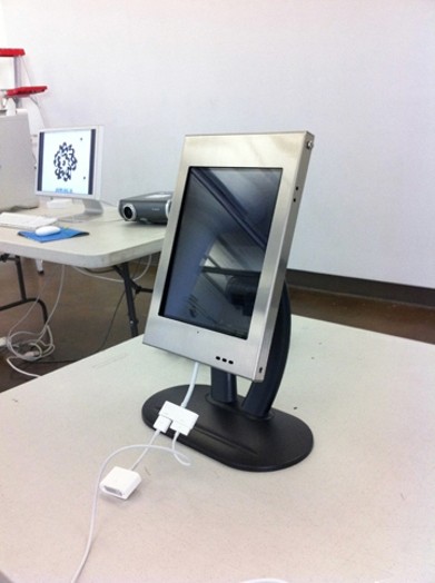 A photo of a pc screen with white cables put on a bench.