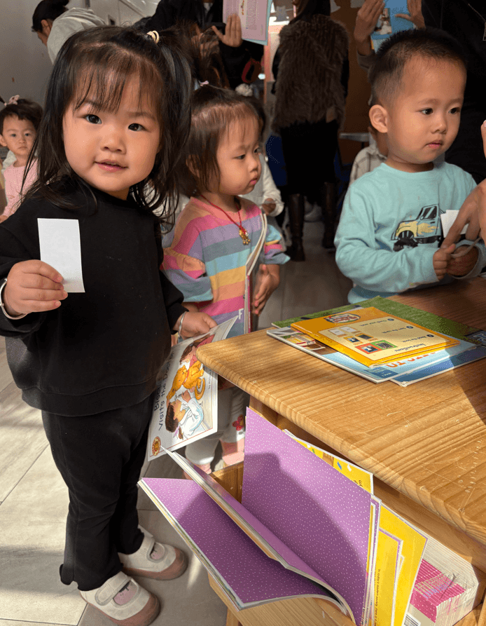 A preschooler uses fake money to buy a book. 