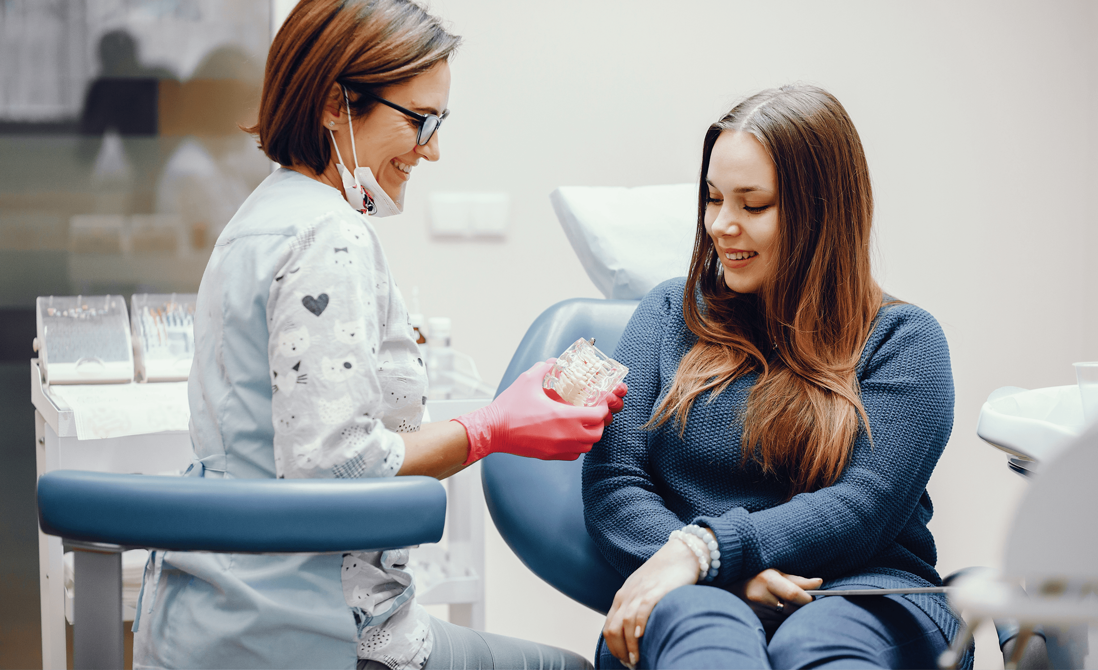 Dentist discussing dental check-up with a female patient using a tooth model