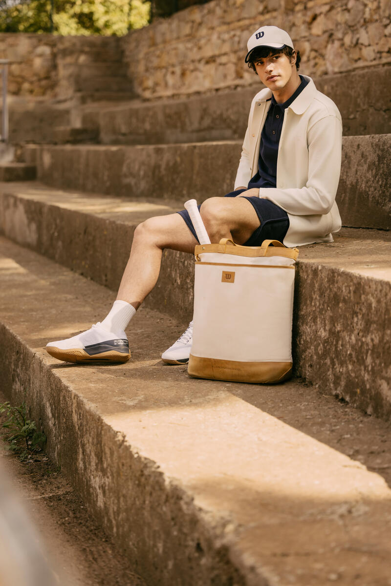 Un mannequin en total look Wilson Courtstyle, inspiré parl'univers du tennis, avec sac en toile blanche, short bleu, blouson et casquette blanche