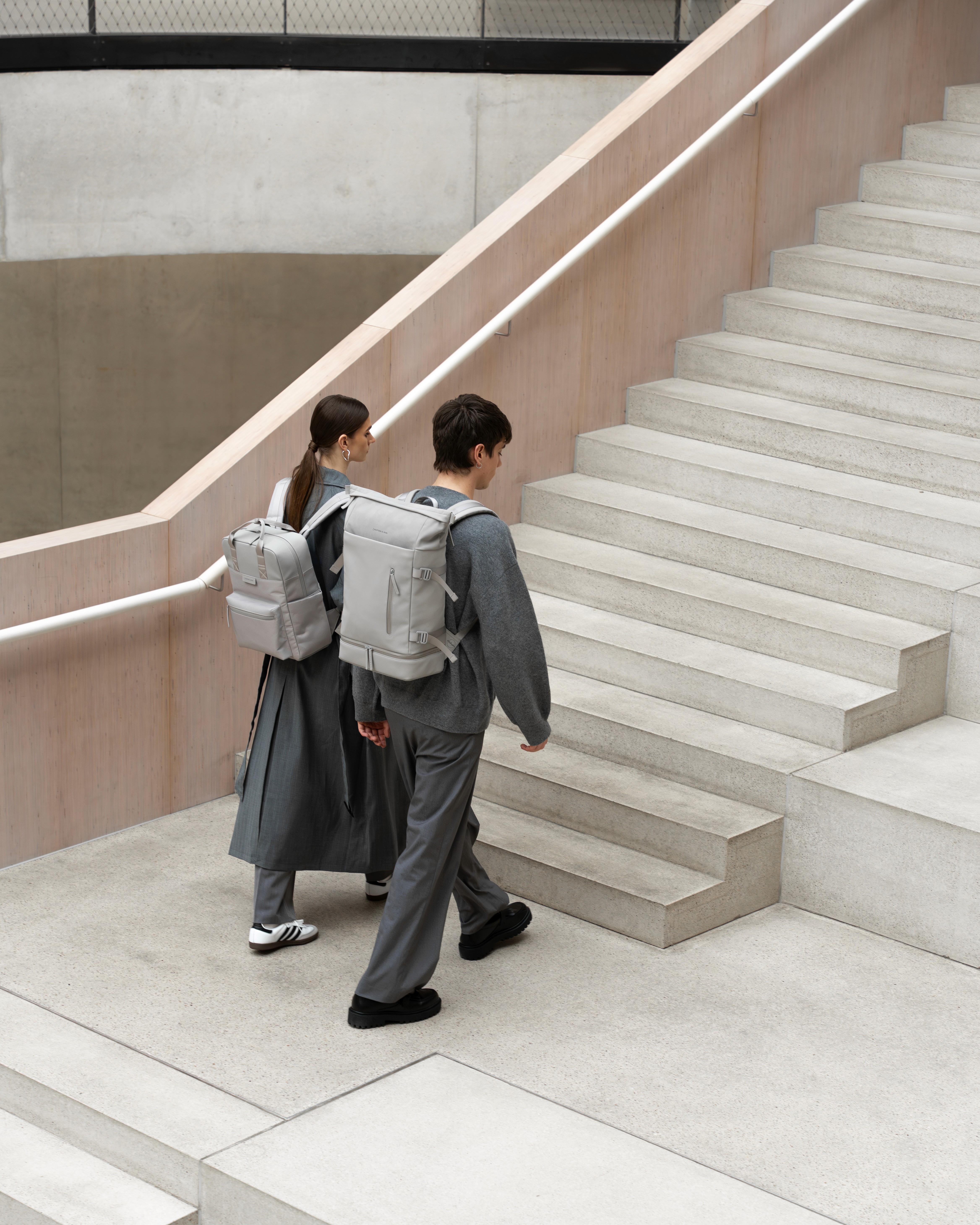 Deux mannequins montent des marches en portant sur le dosdes sacs à dos