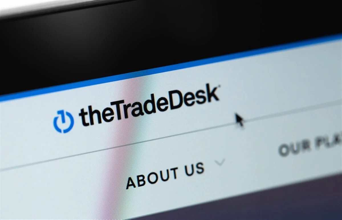 The Trade Desk logo displayed on a website interface, featuring a blue icon and black text, with navigation links such as "About Us."