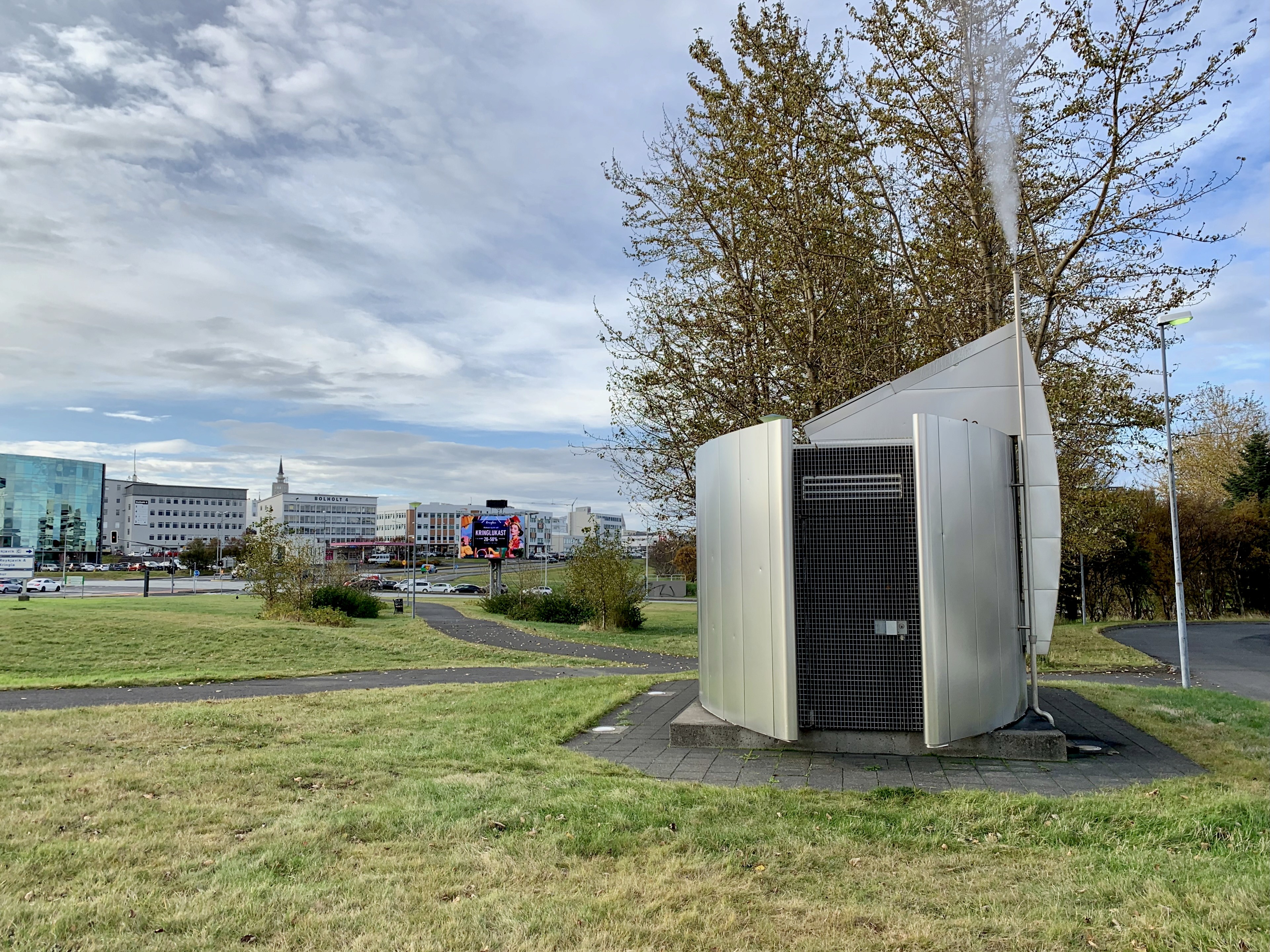 Geothermal borehole structure in central Reykjavík, with steam rising from a modern vent installation, showcasing the city’s use of geothermal energy directly beneath the urban landscape for heating and hot water.