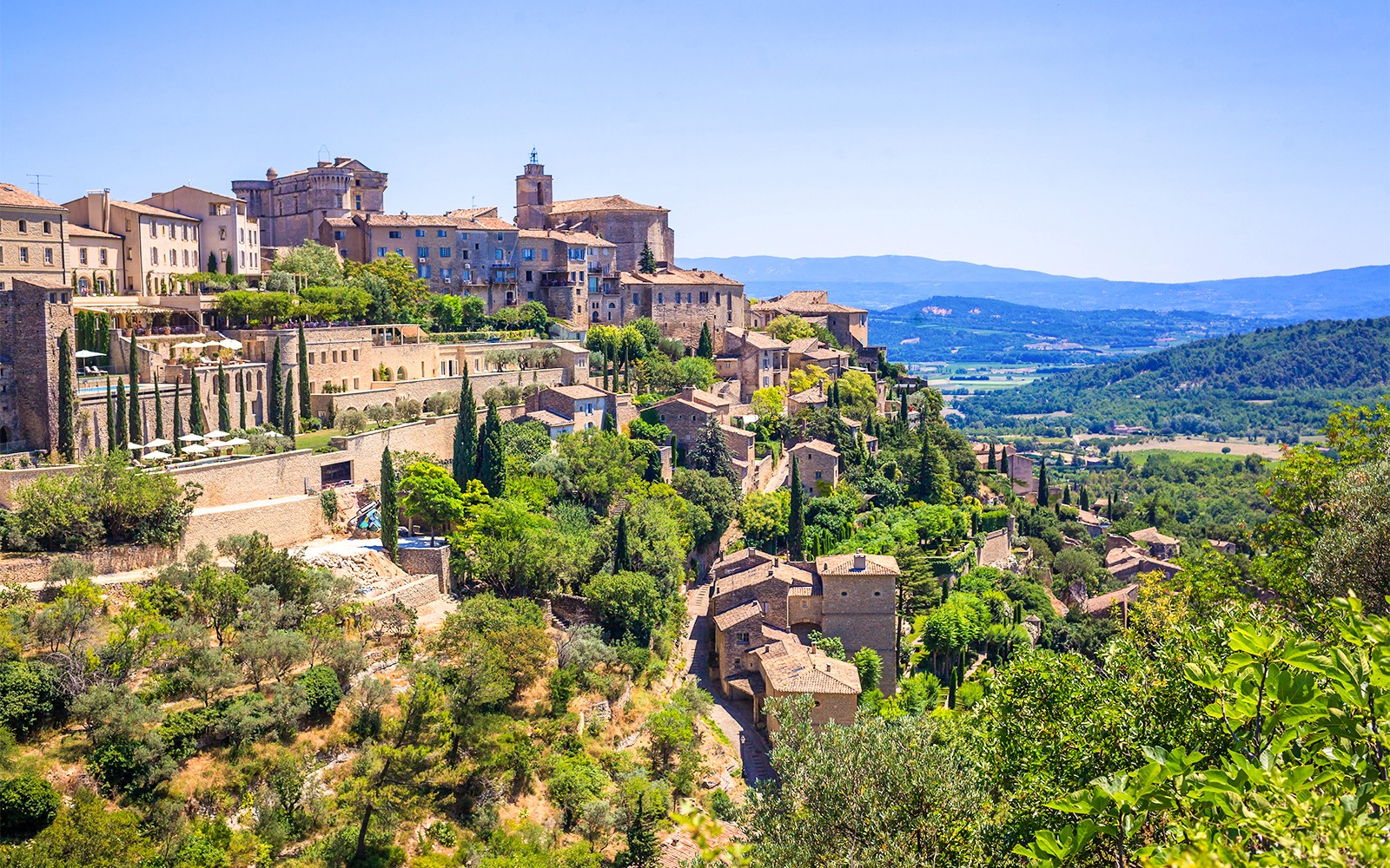Hilltop village of Gordes in Provence with stone buildings and lush greenery.