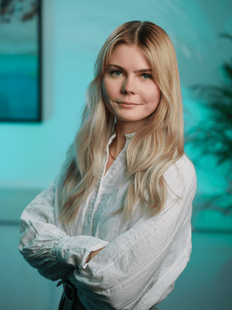A young man in a white t-shirt stands against a light-colored background.