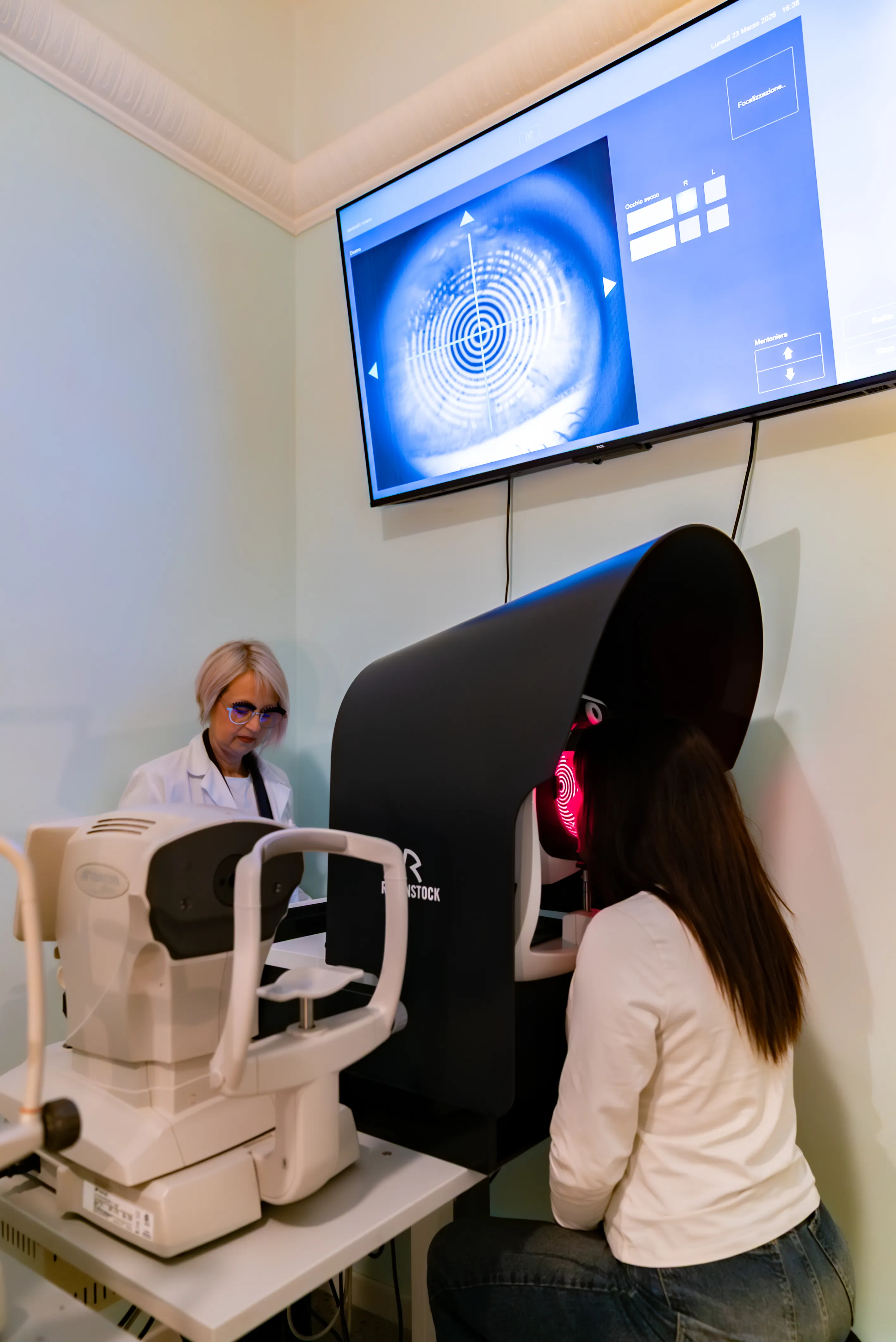 Cliente durante una misurazione biometrica dell’occhio con DNEye Scanner Rodenstock, eseguito da Cristina Notarangelo presso Ottica Dentella ad Ancona. La tecnologia DNEye Scanner permette di rilevare migliaia di punti di misurazione e numerosi parametri oculari utili alla progettazione di lenti biometriche personalizzate, con l’obiettivo di ottenere una visione più nitida, naturale e precisa e una soluzione ottica calibrata sulle caratteristiche individuali dell’occhio.