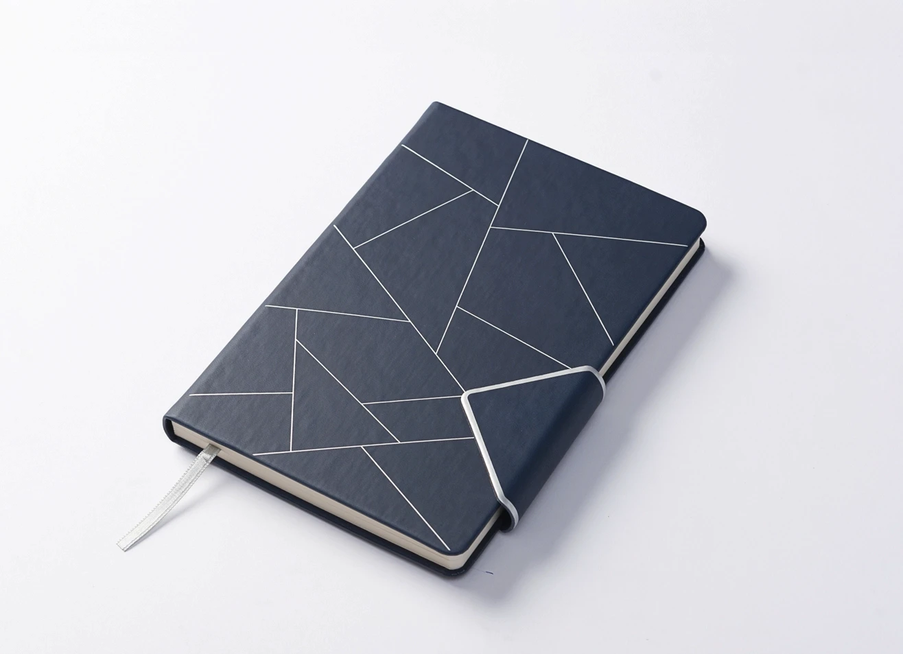 Angled view of geometric pattern journal with strap detail and ribbon bookmark