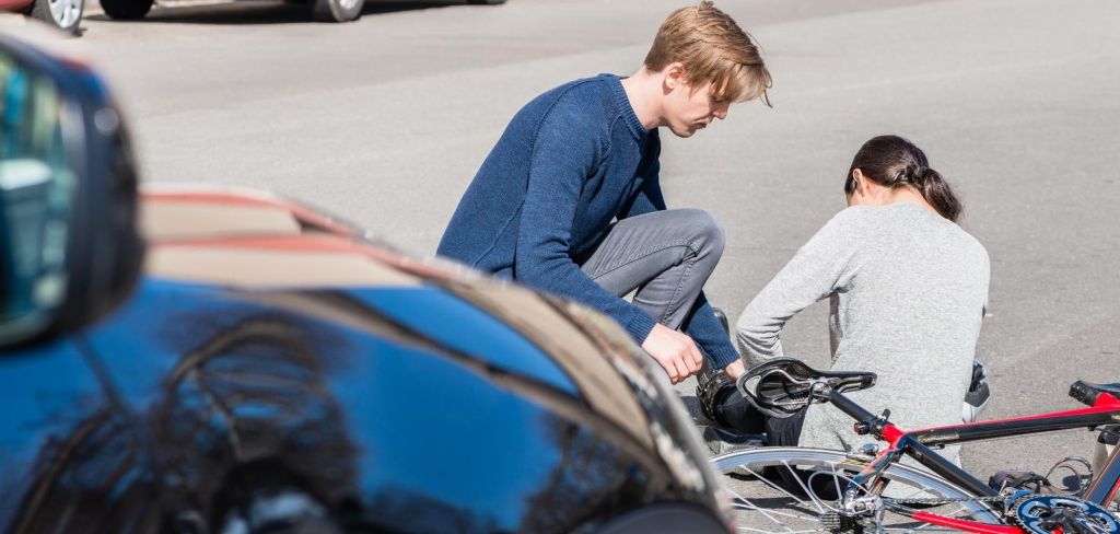 helpful young man giving first aid to an injured woman after bicke accident