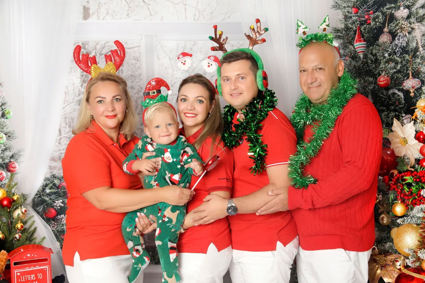 Cute family with grandparents wearing red, posing with head props for a Christmas photoshoot in Dubai by Mahvin Photography studio