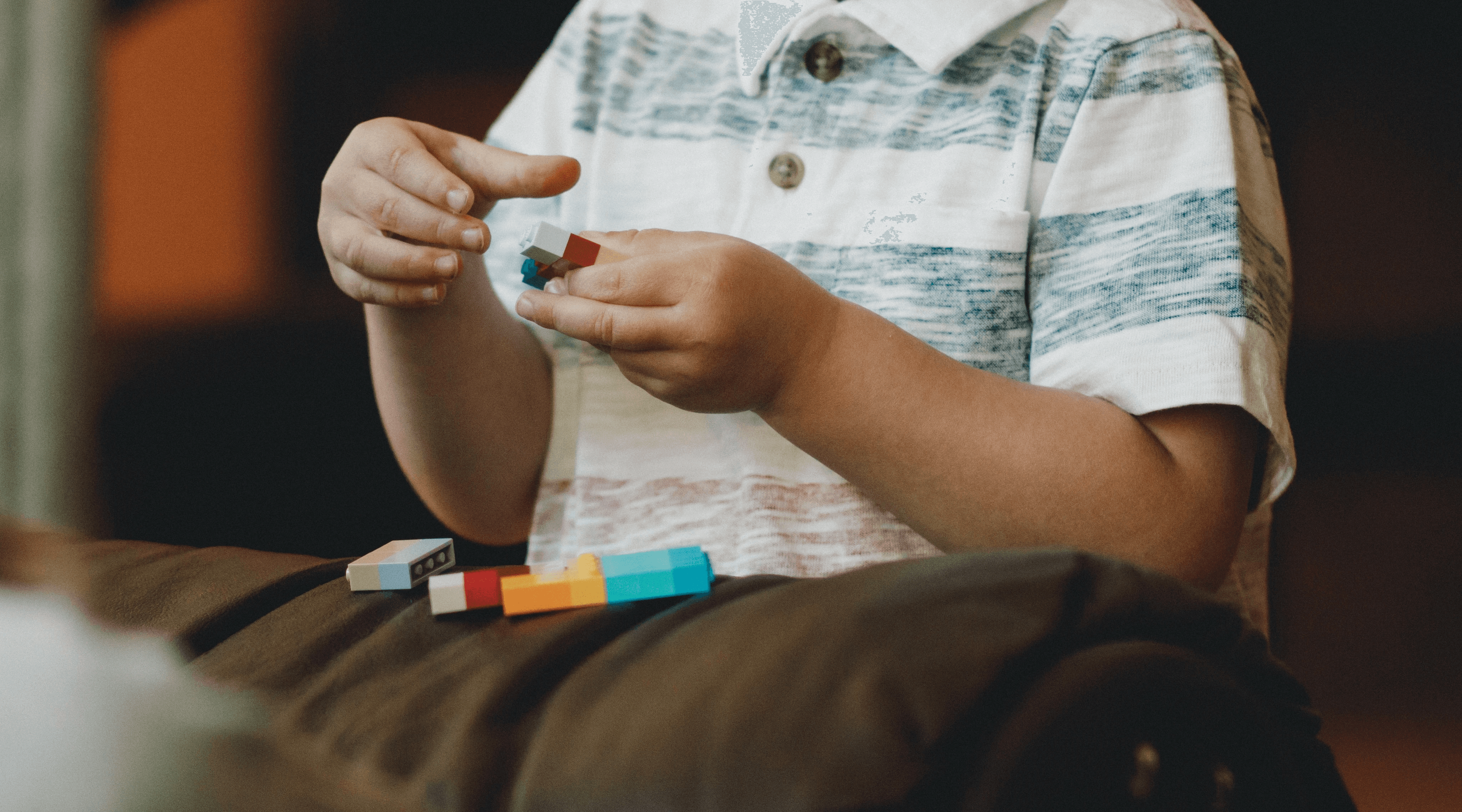 A child playing with blocks on the end of a couch 