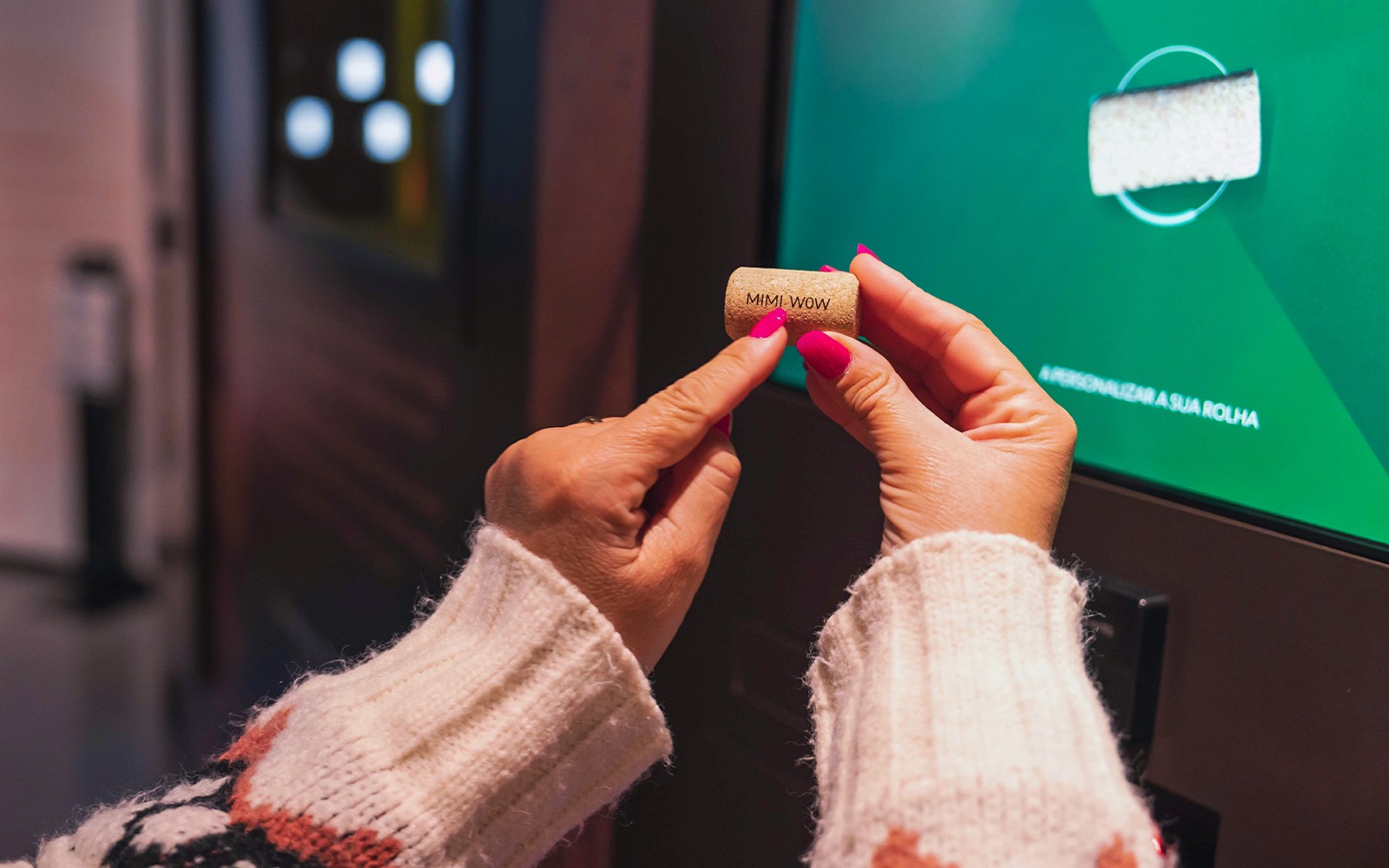 Kezek, amelyek egy parafadugót tartanak "MMI WOW" felirattal a Planet Cork kiállításon.