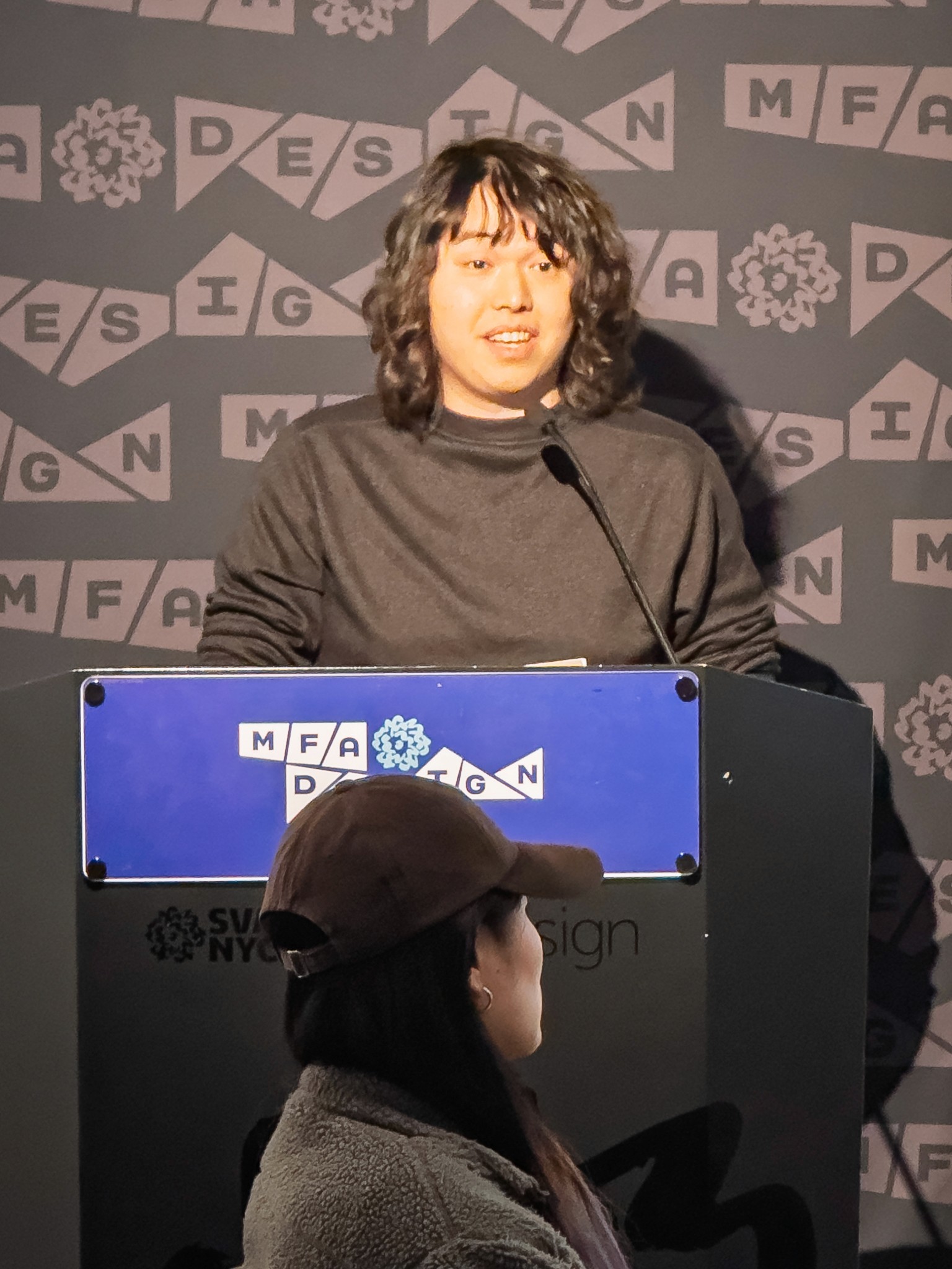 Man at a podium with microphone, delivering a slide presentation