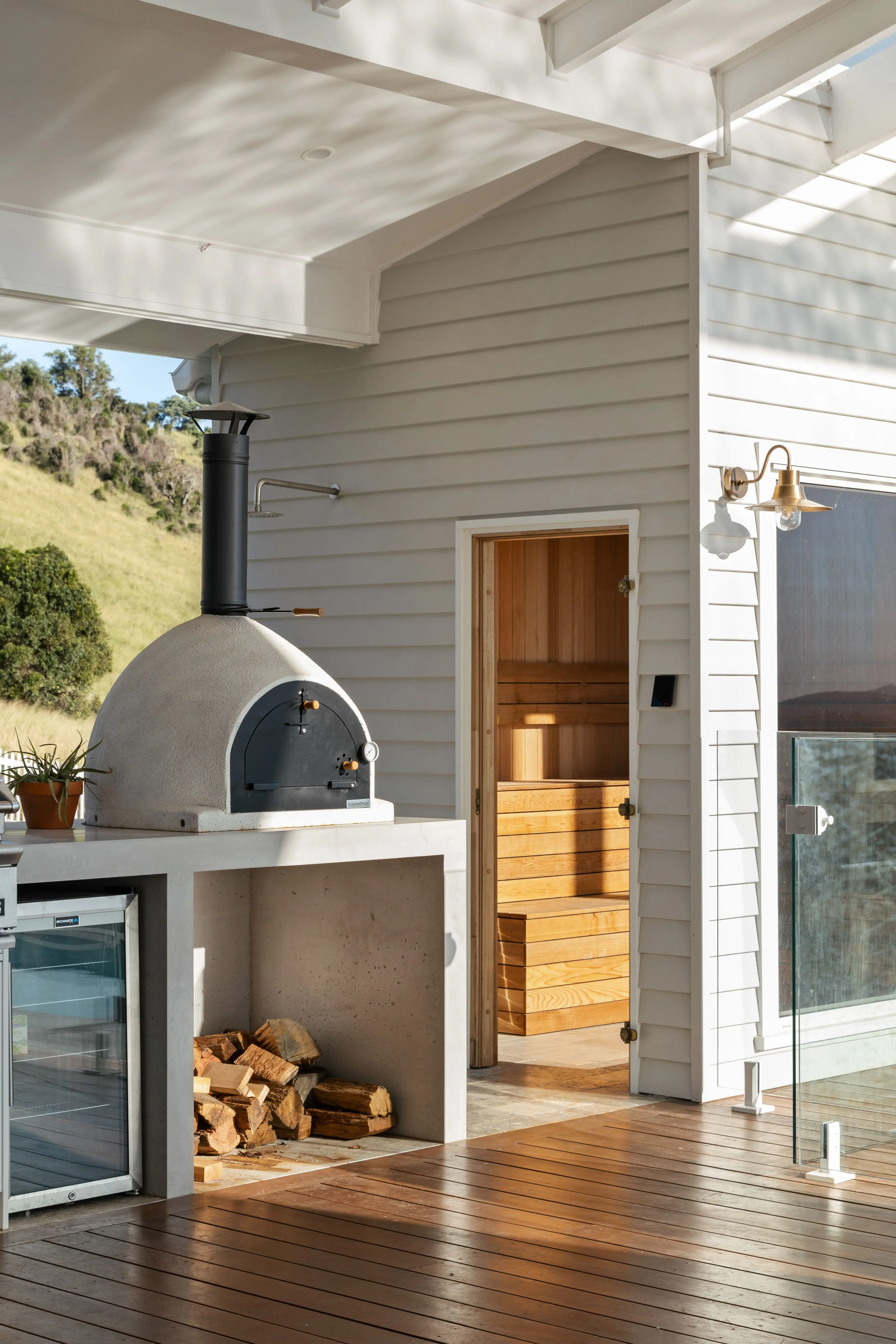 A pizza oven in the outdoor entertainment area with a sauna in the background
