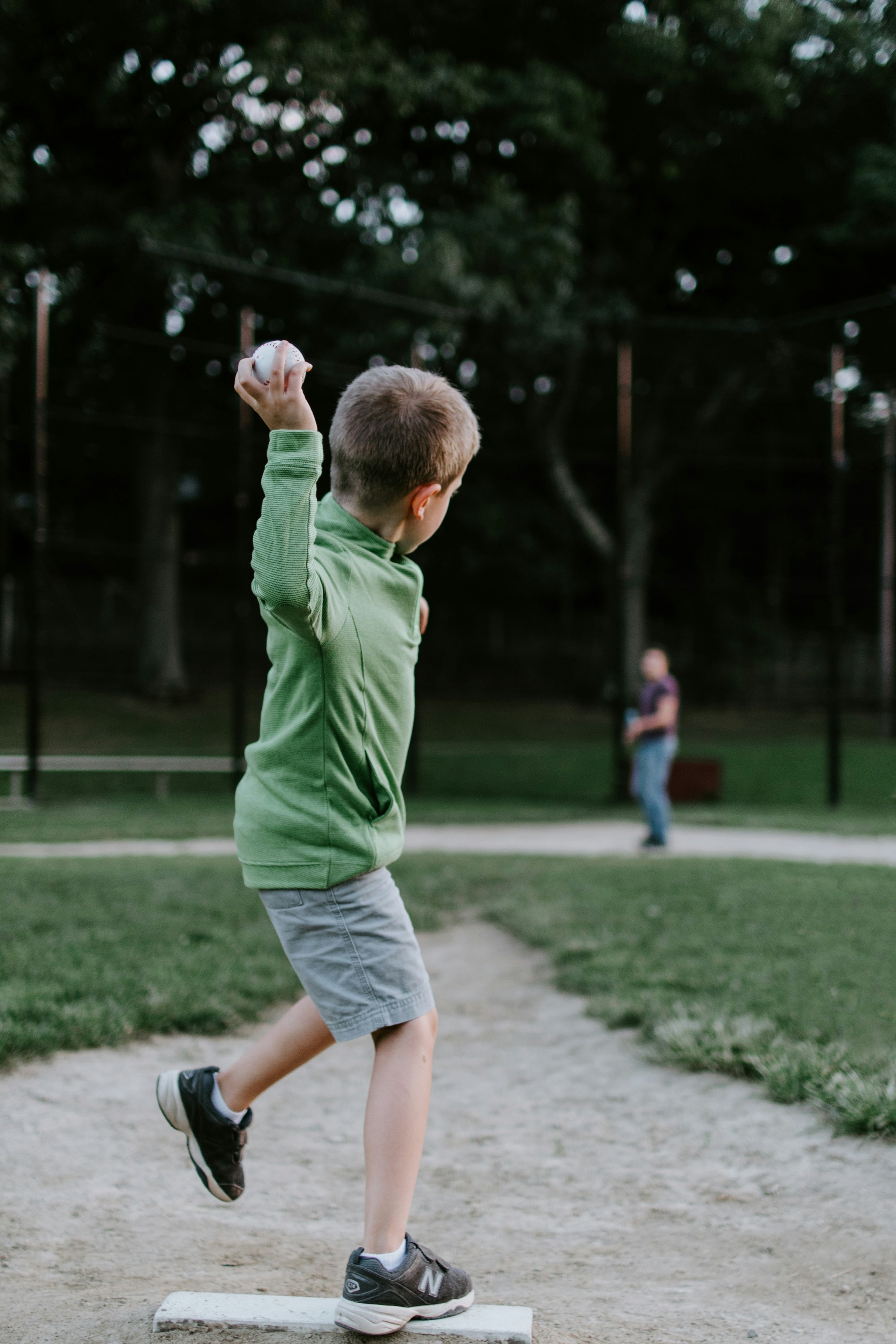 A child throwing a baseball at another person in a park