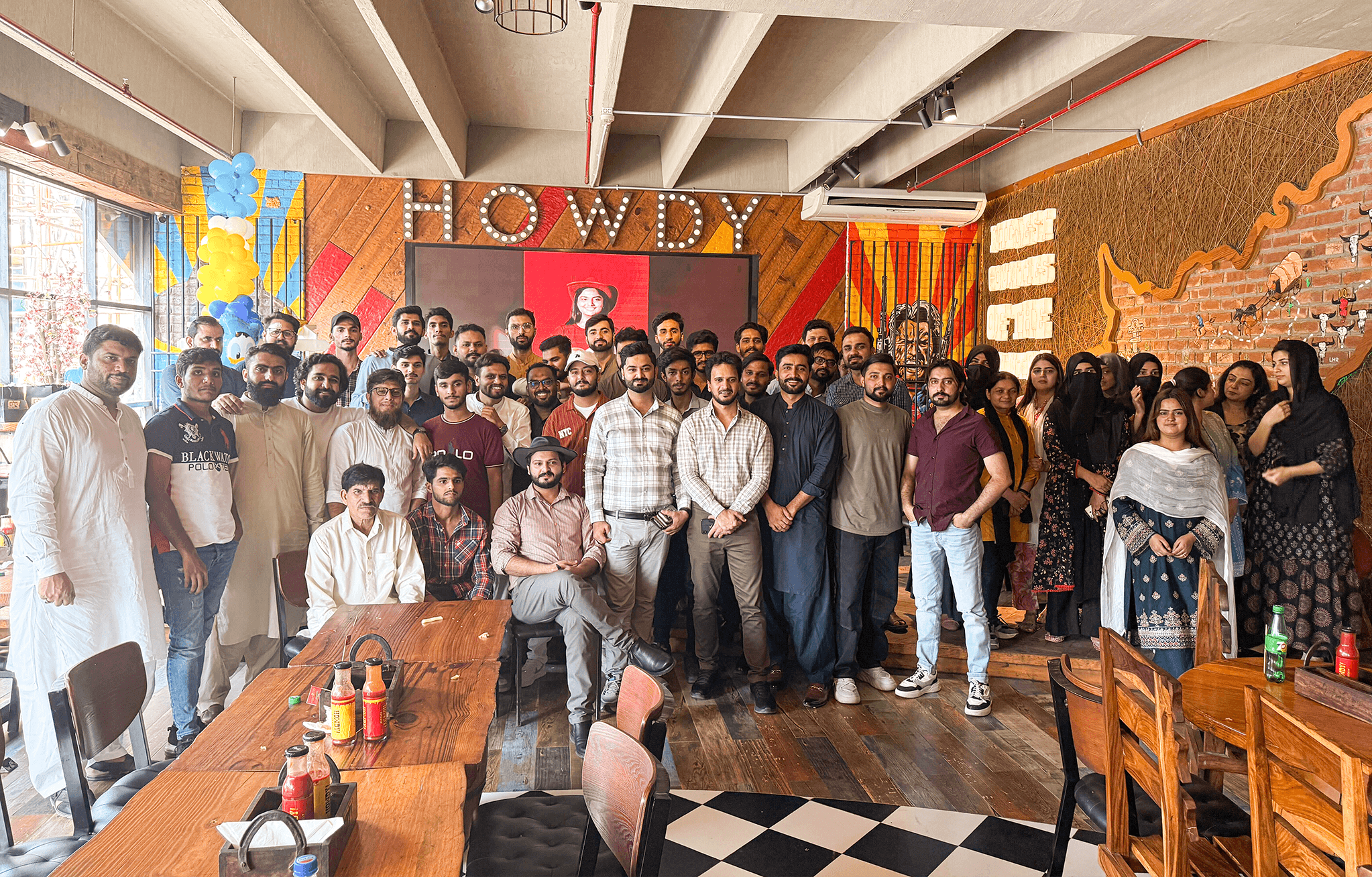 three men sitting while using laptops and watching man beside whiteboard