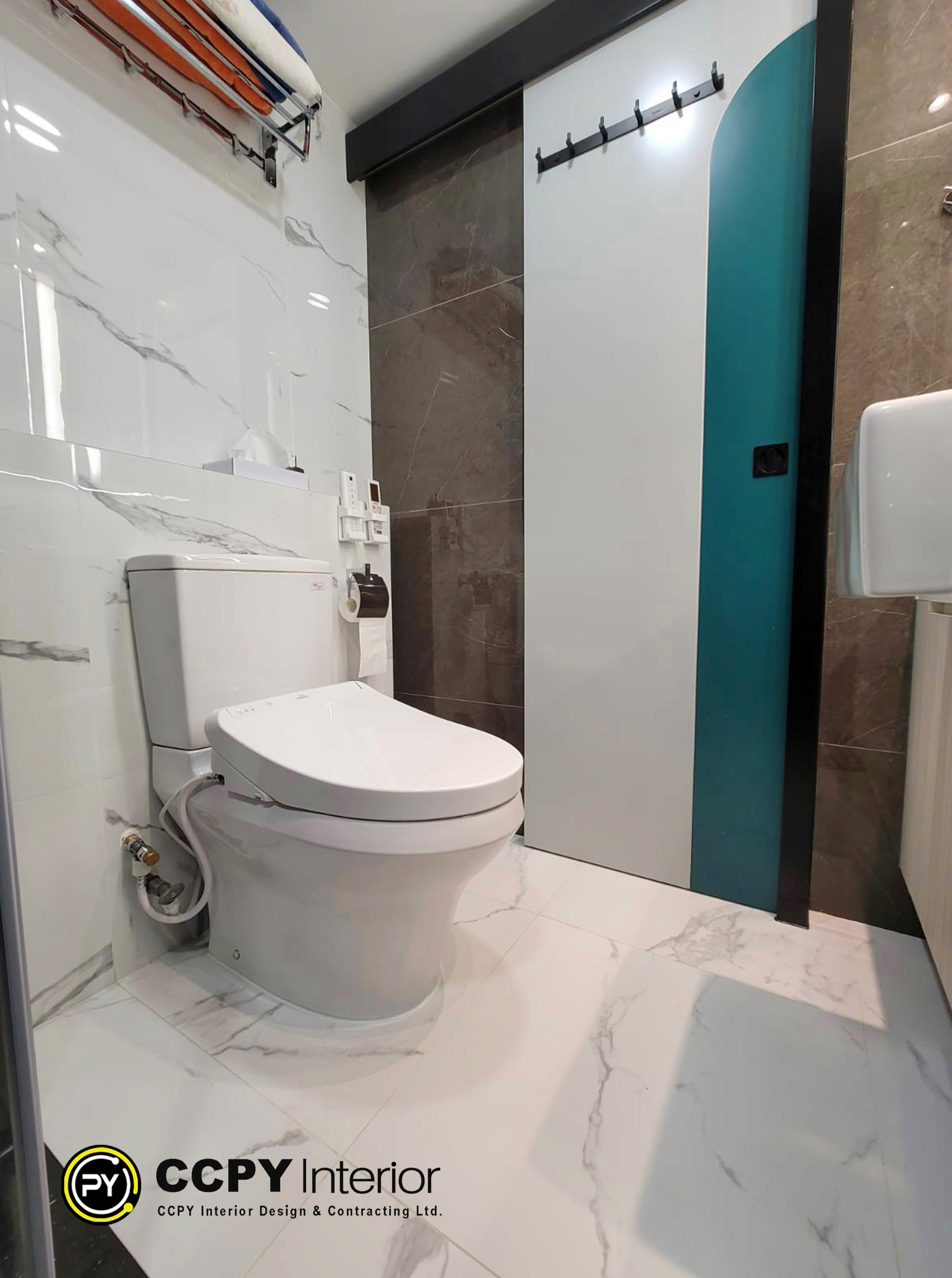 The selected region shows a modern bathroom featuring a TOTO smart toilet integrated into a compact, contemporary layout.Key Features VisualizedSmart Toilet: White intelligent toilet system with an electronic bidet seat, water connection hose, and side control panel.Cabinetry & Storage: Sleek, handle-less gray vertical cabinets maximizing narrow spatial efficiency.Wall Tiling: Large-format, dark stone-texture porcelain tiles providing a premium, tactile backdrop.Fixtures: Standard wall-mounted toilet paper holder positioned within easy reach of the smart seat.