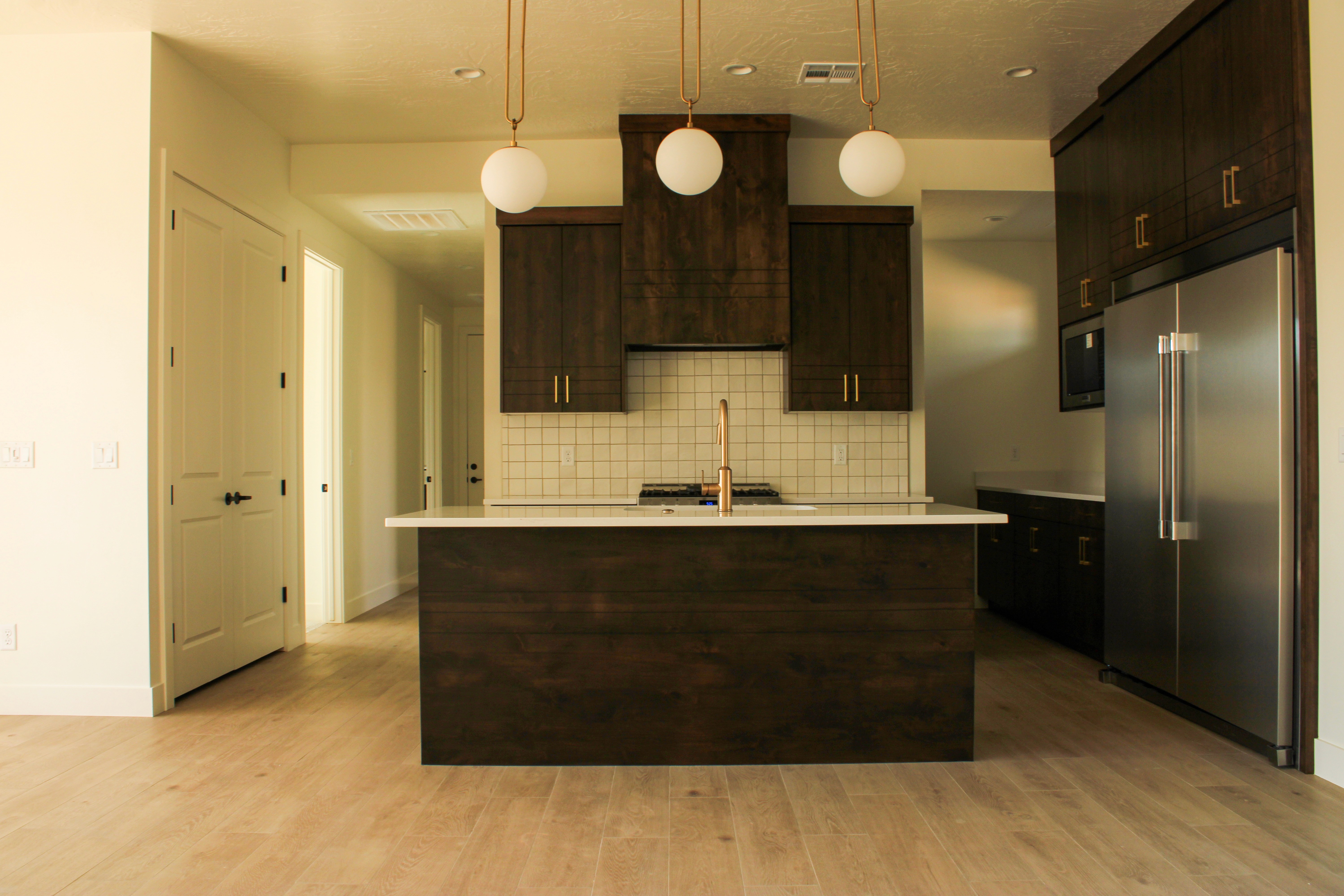 Kitchen island and dark stained wood cabinetry at The Overlook at Falcon Ridge in Hurricane, Utah, featuring bronzed gold hardware and custom finishes.