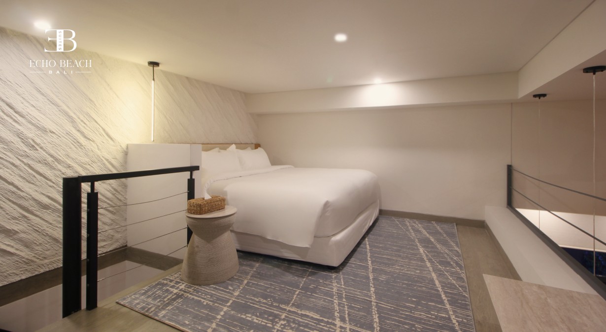 Master bedroom on the Mezzanine level of the Echo Beach Suite apartment in Canggu, Bali, featuring a white bed and a stylish textured wall finish.