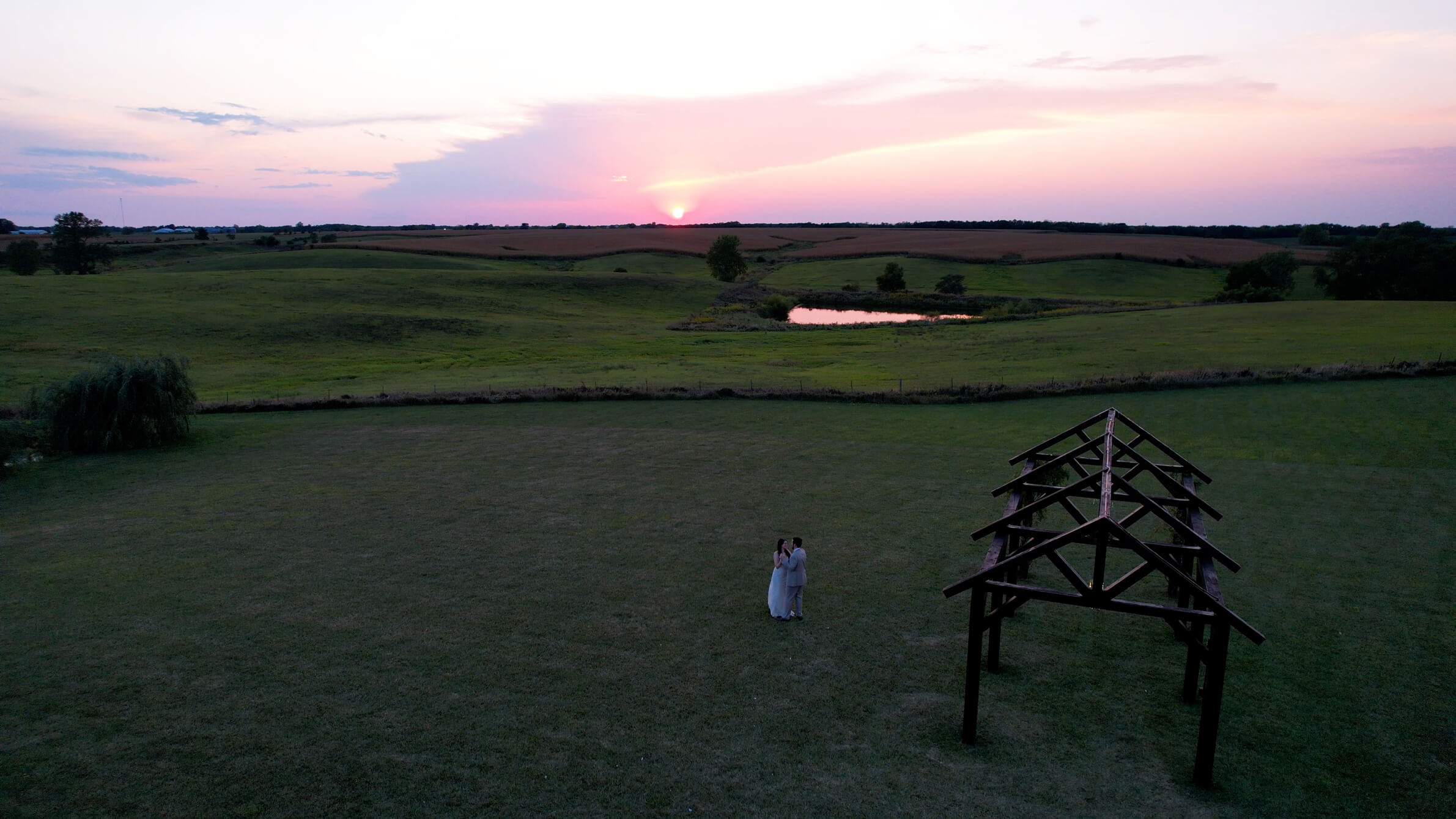 A drone shot of a bride and groom slow dancing as the sun sets
