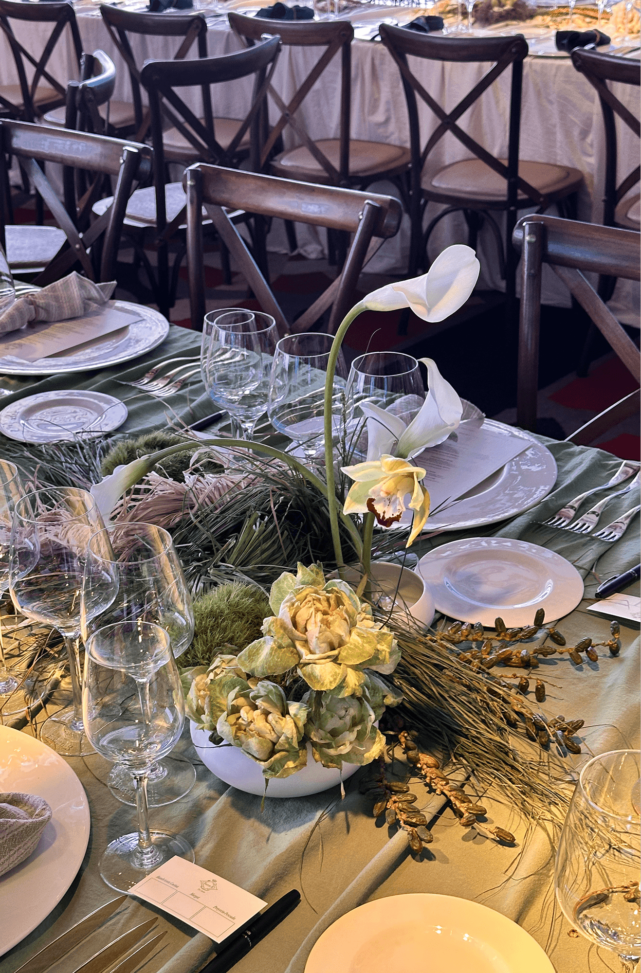 Arreglo floral con planta cebra, orquídeas blancas y rafia natural para decoración de mesas botánicas.