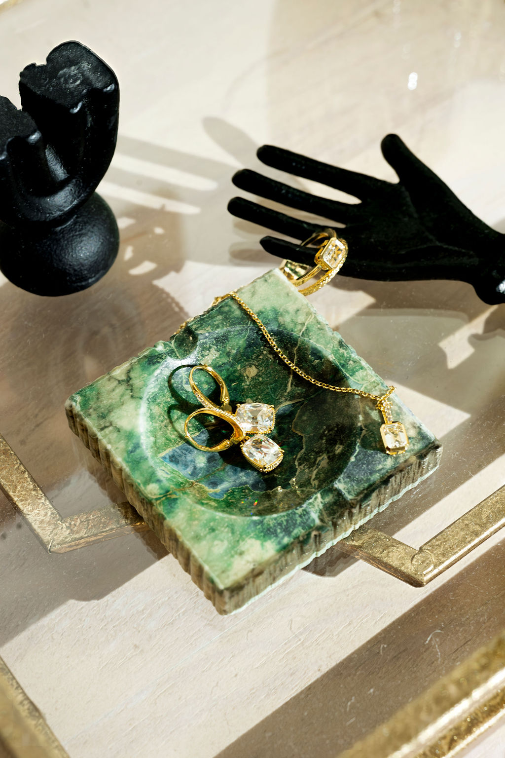 jewelry photography of gold and diamond earrings with a set, placed on an emerald green dish.