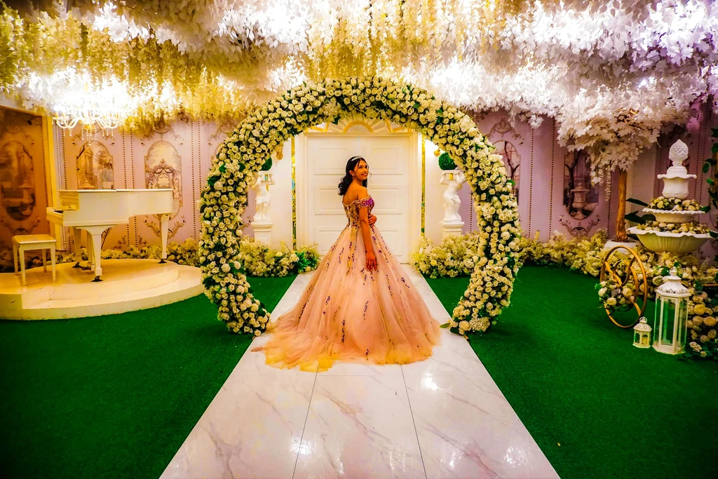 Debutante in a blush gown on the aisle beneath the arch at Celestia Hall