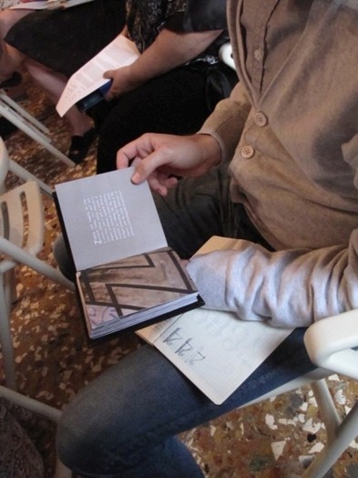A photo of a person trying to replicate in his notebook the image from an opened book.