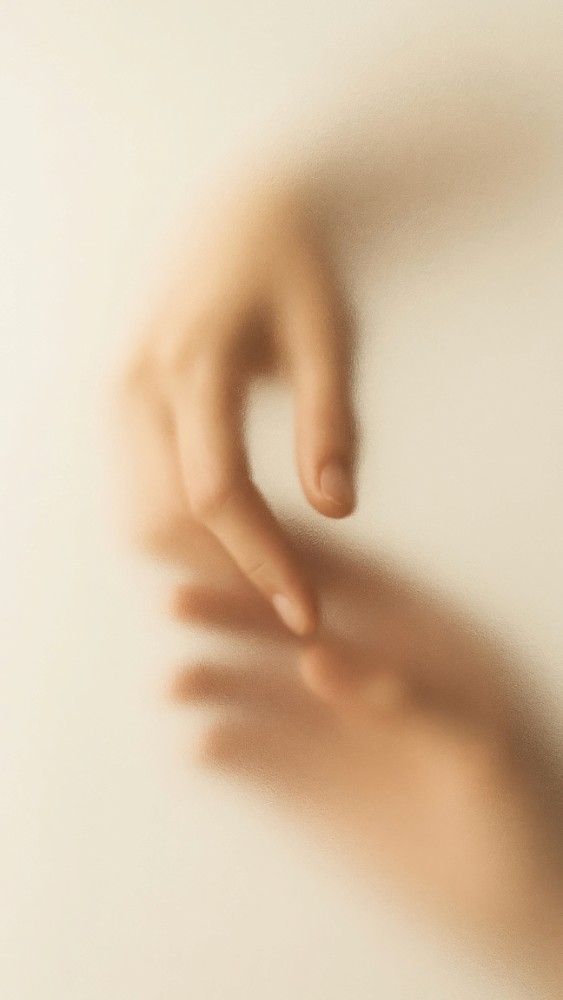 Soft-focus image of a hand reaching forward, symbolizing connection, care, and human presence.