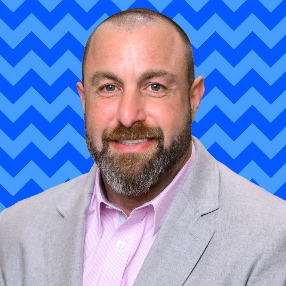 Our people in light blue hoodies putting their hands together outside, symbolizing teamwork and unity.